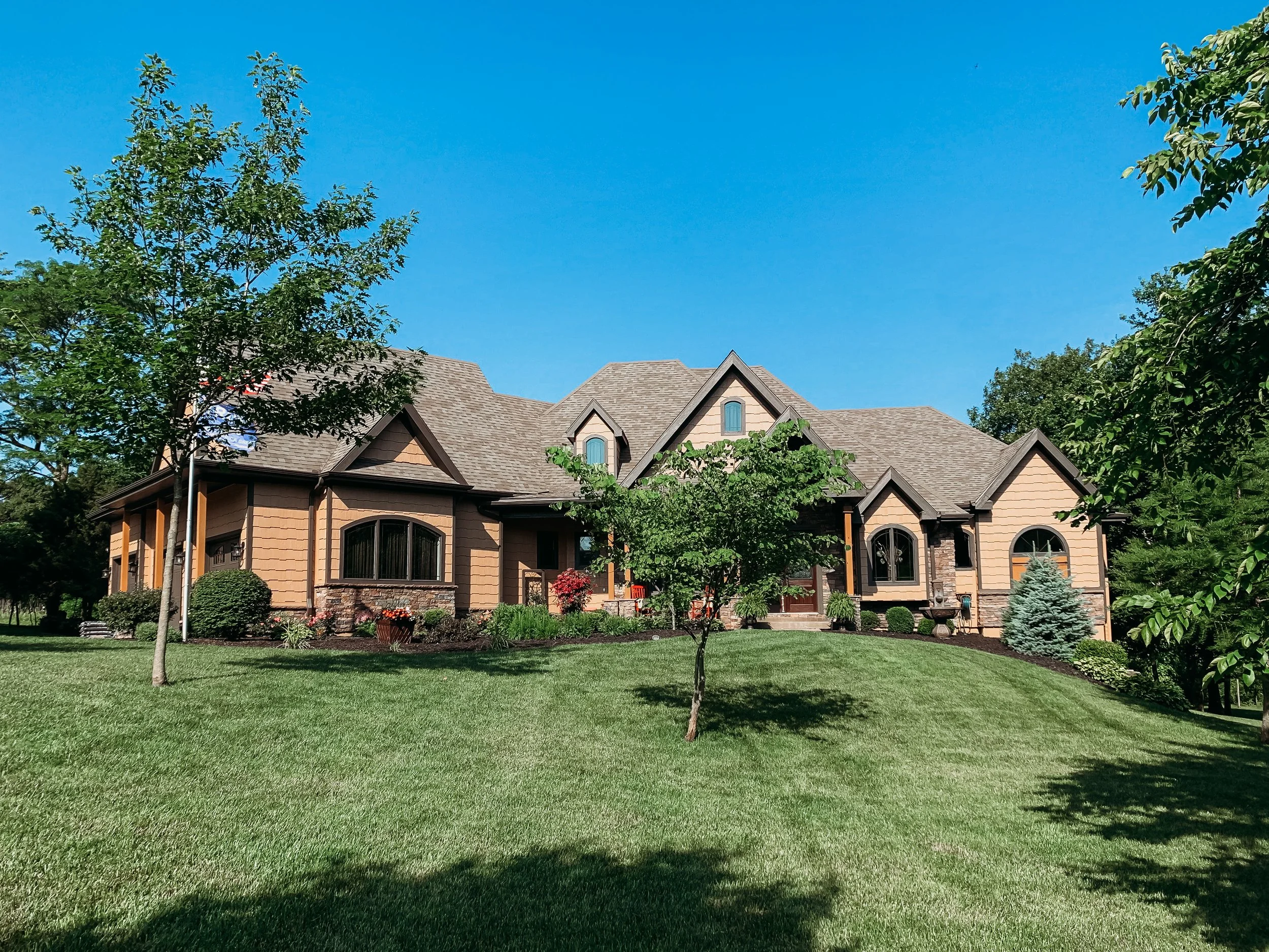 Johnson County home with a tan exterior, stone accents and dark window trim.