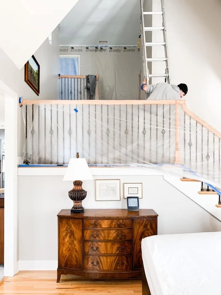 Protected stair railing and adjacent finishes during interior painting in Falcon Lakes.