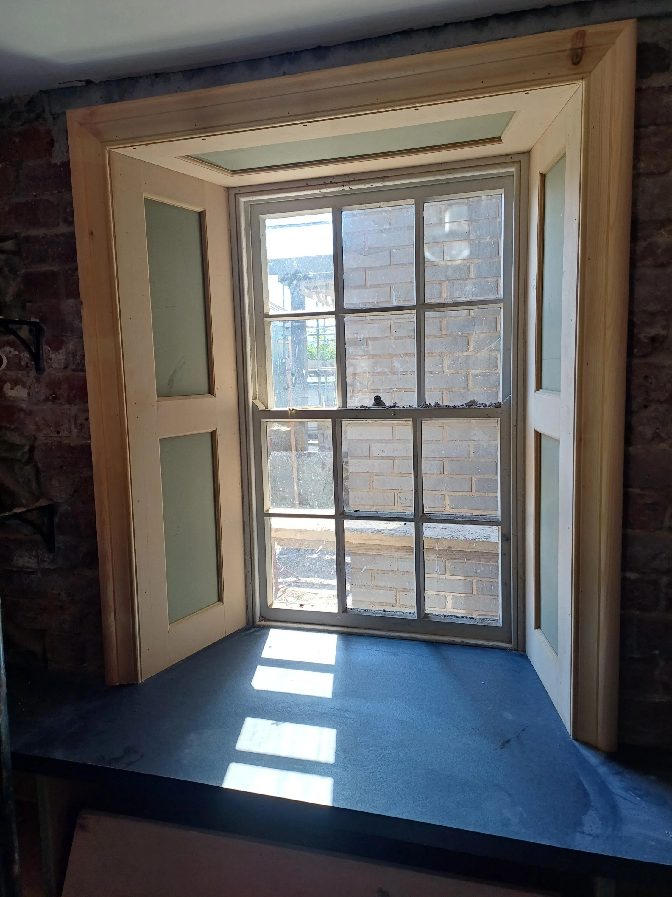 THIS is a new wooden window surround that was made and installed to match the original paneled windows 