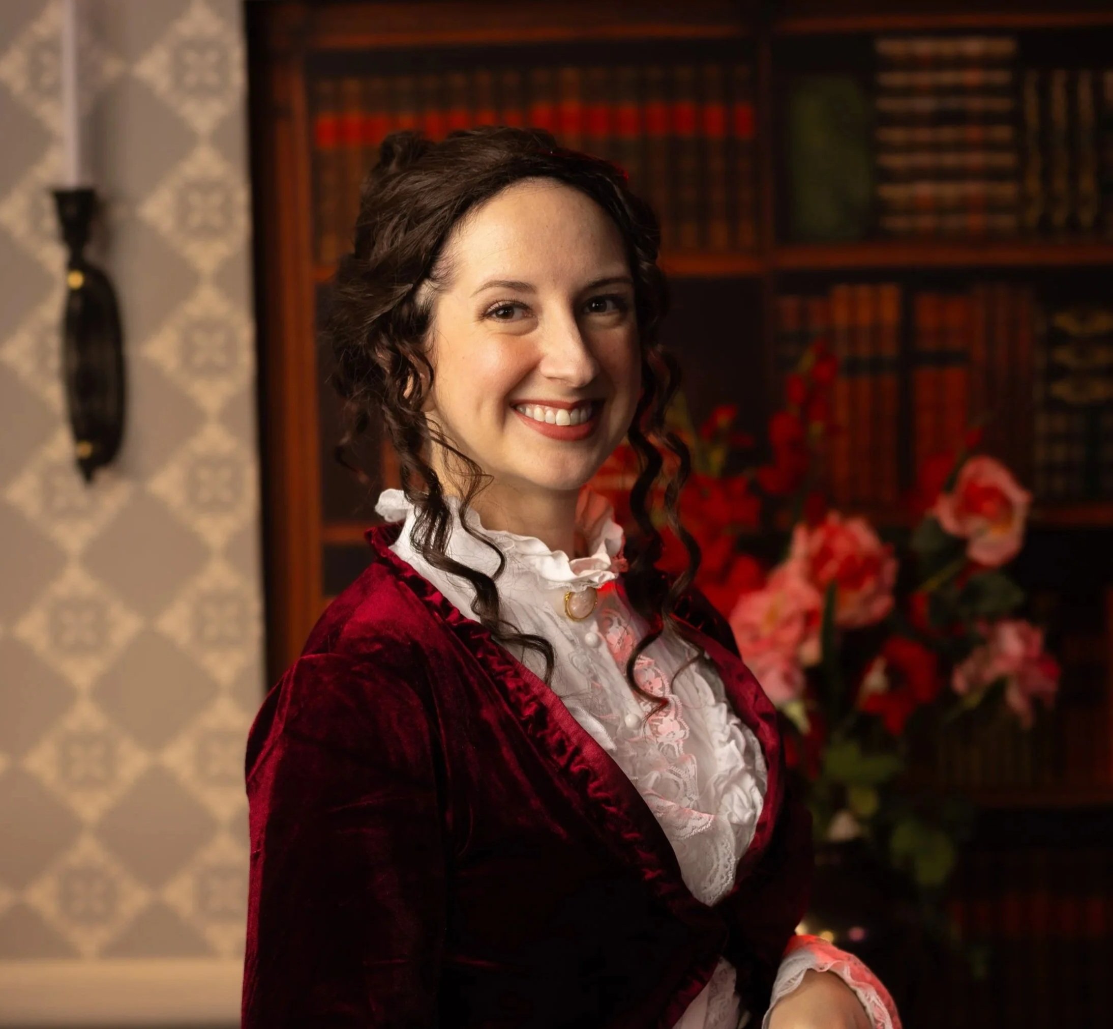 Photo of a smiling woman with brunette hair wearing a white shirt and a red coat