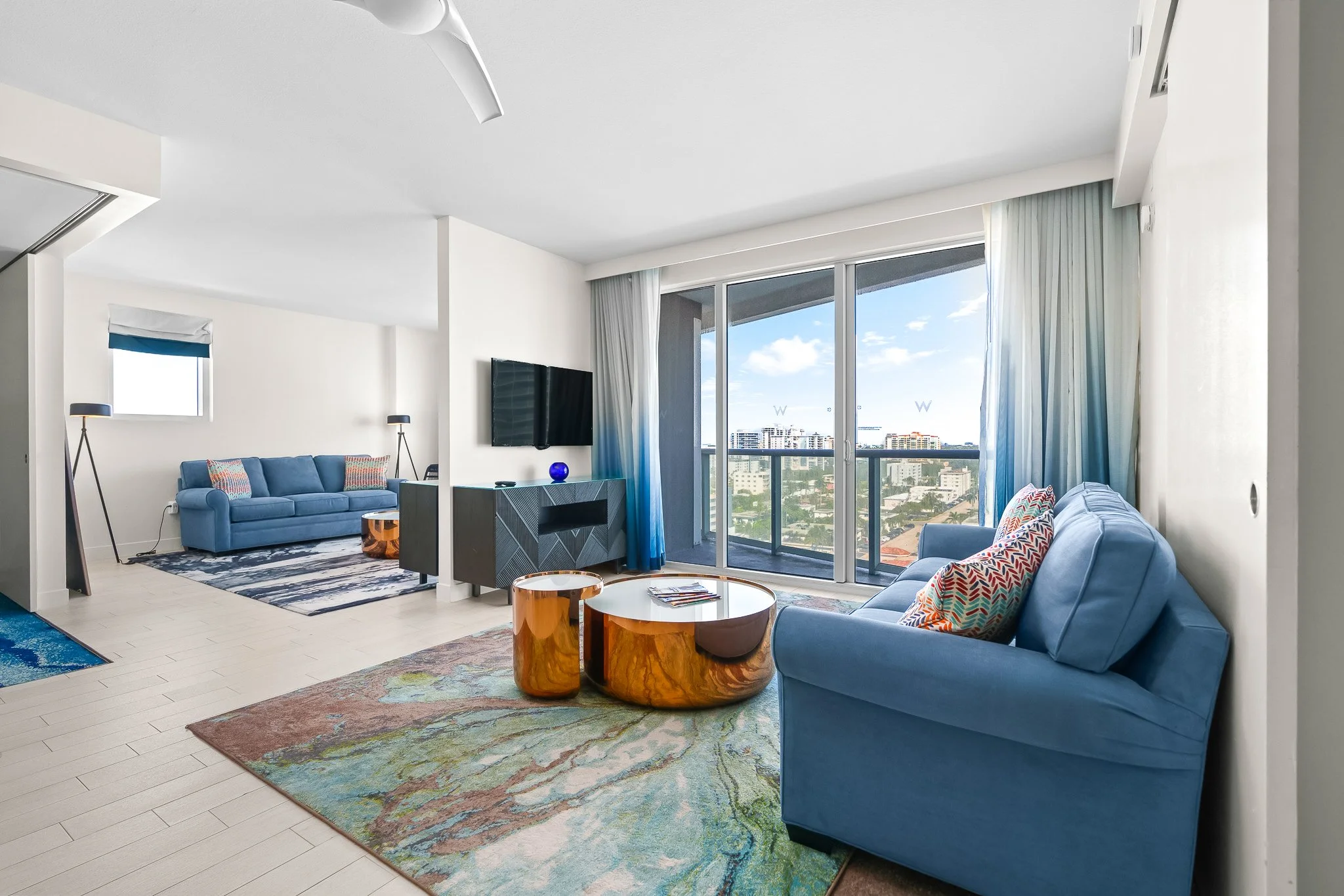 Hotel suite living room with teal sofa and coastal artwork in South Florida resort