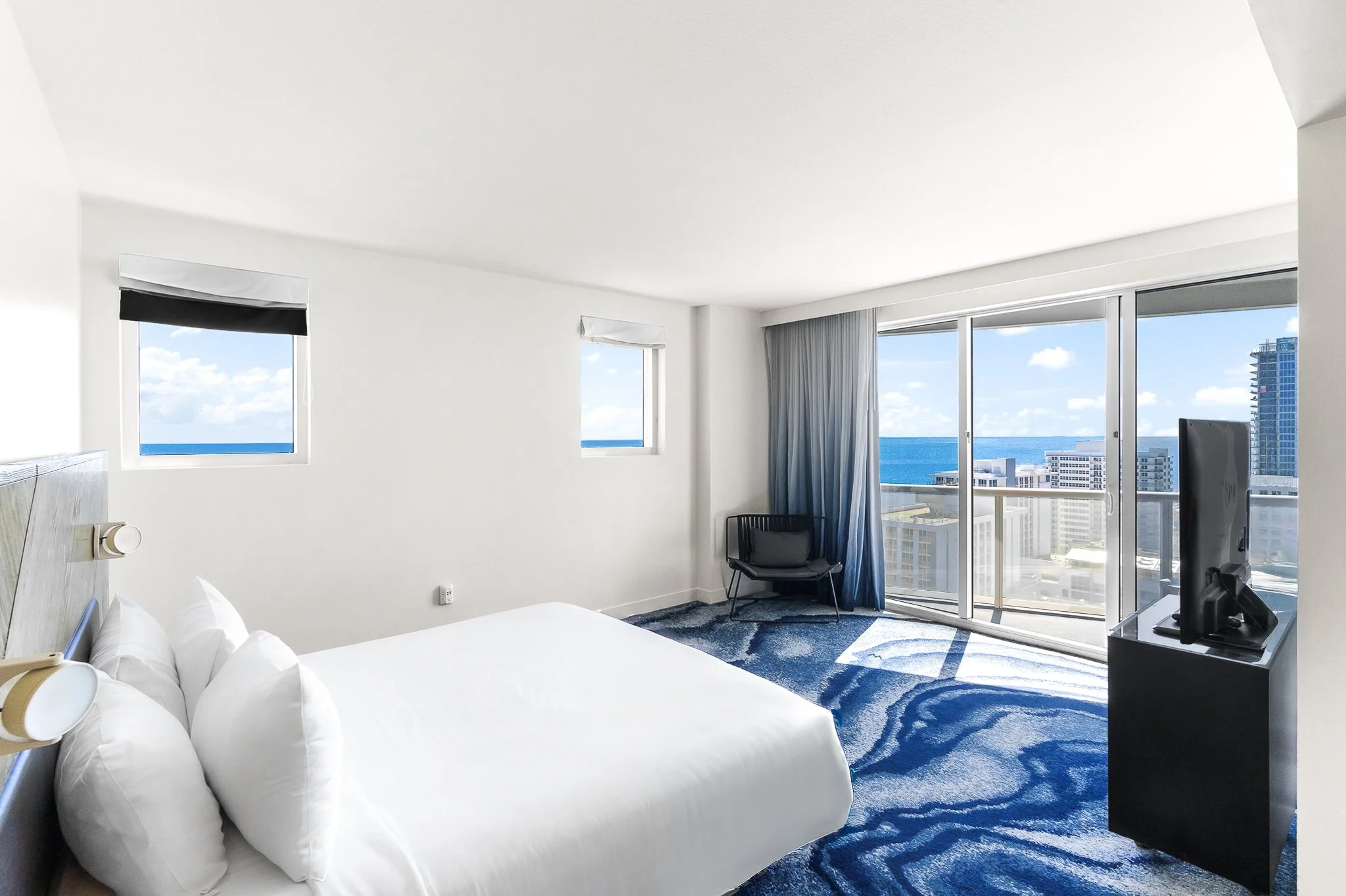 Hotel guest room with white bedding and ocean views in a South Florida resort