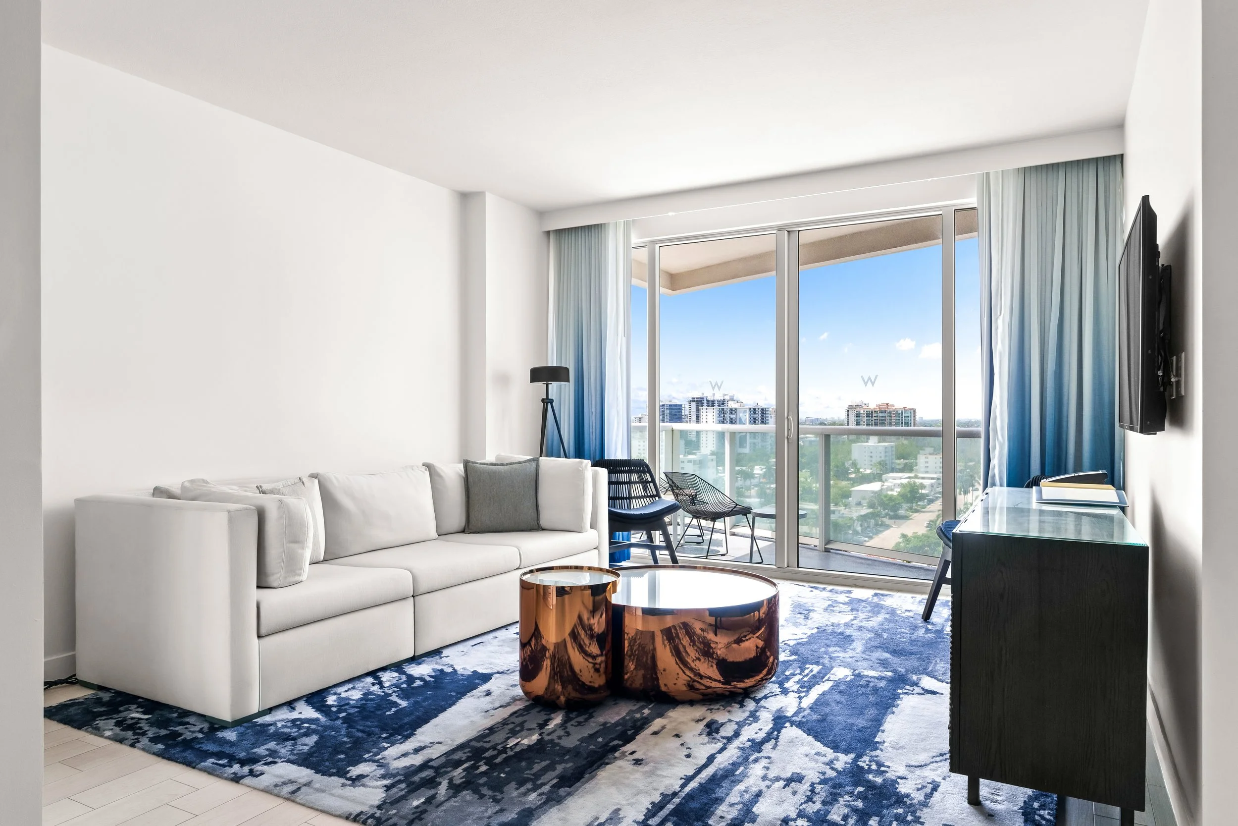 Hotel suite living area with white sofa, side table, and ocean-view window in South Florida