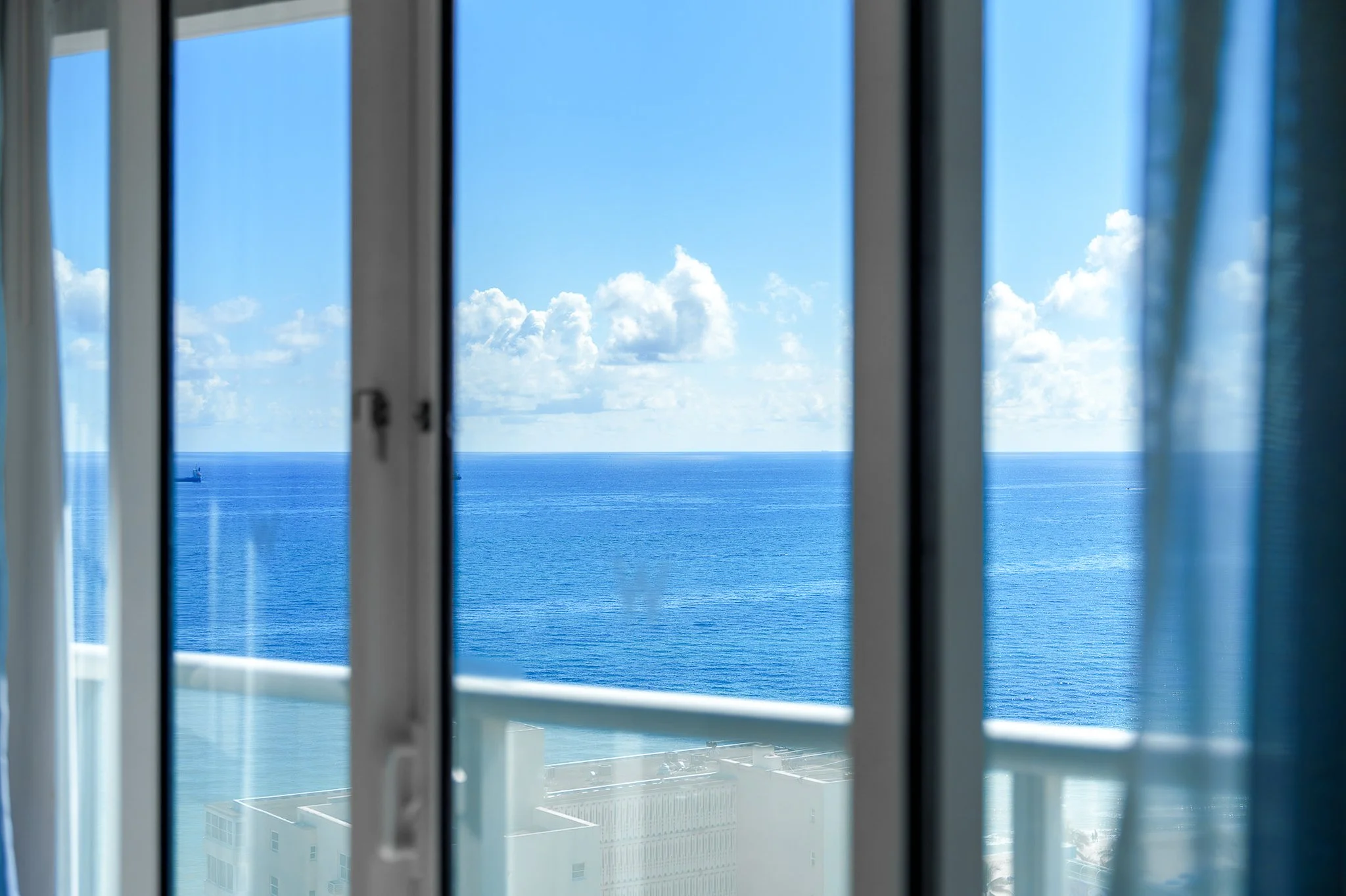 Floor-to-ceiling sliding glass doors with ocean view in a South Florida hotel suite