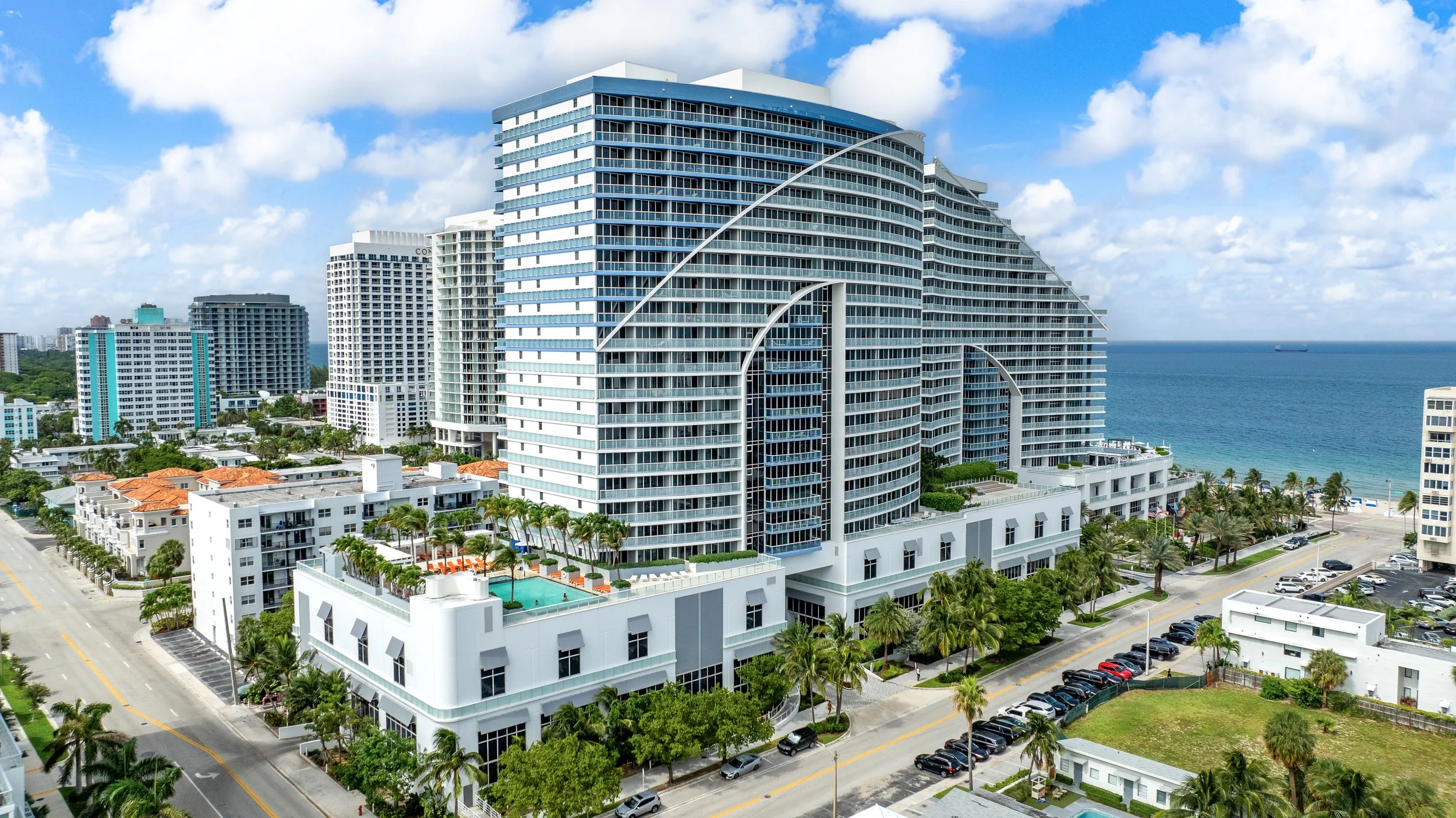 Oceanfront luxury hotel resort with palm trees and white facade on South Florida beach
