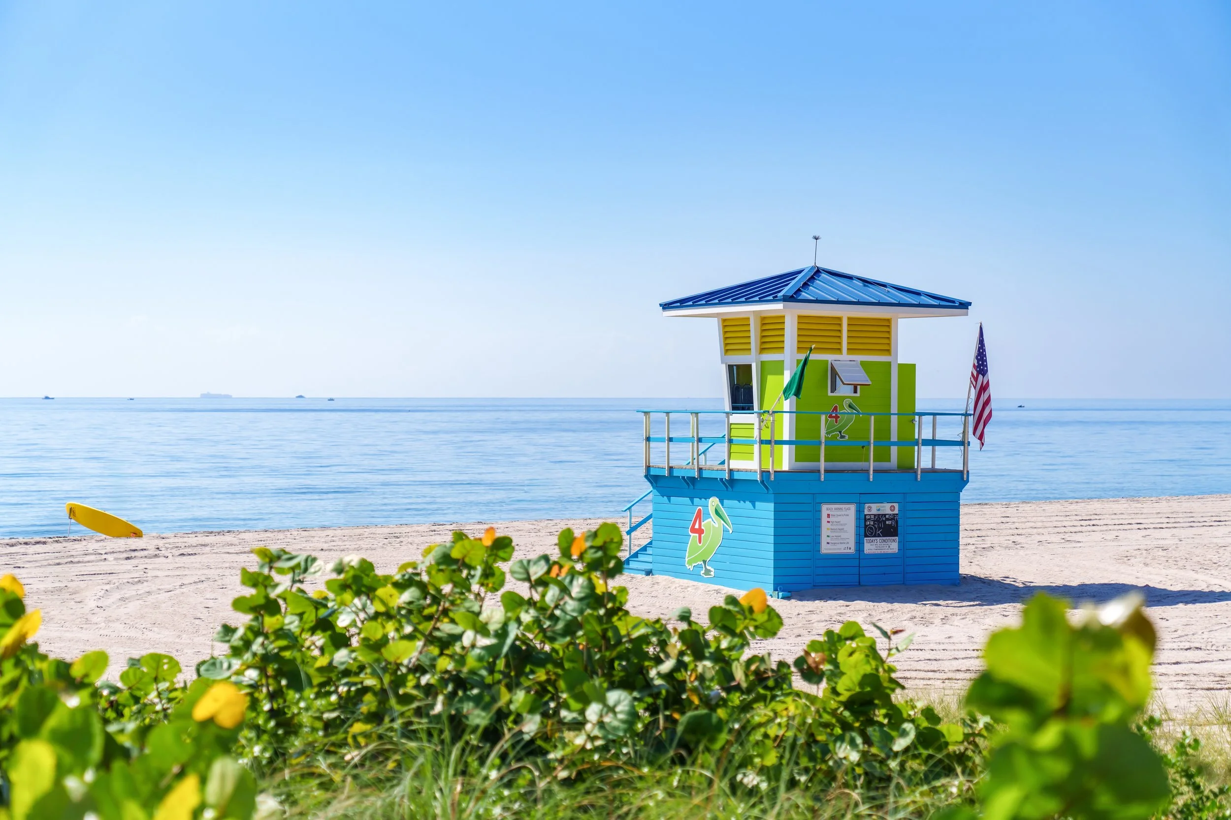 Colorful lifeguard tower on a South Florida public beach with palm fronds