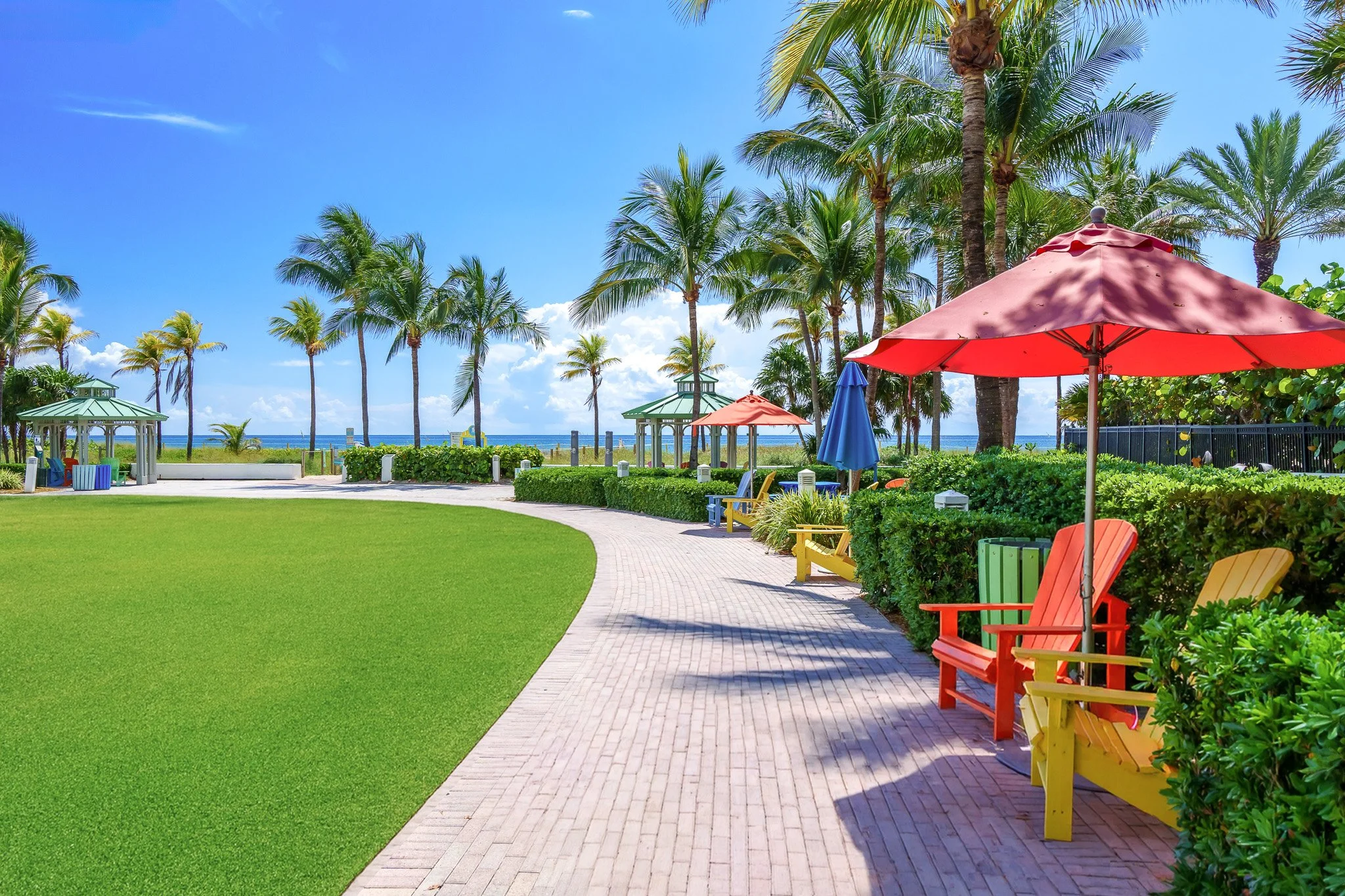 South Florida resort pathway with red beach umbrellas and tropical landscaping