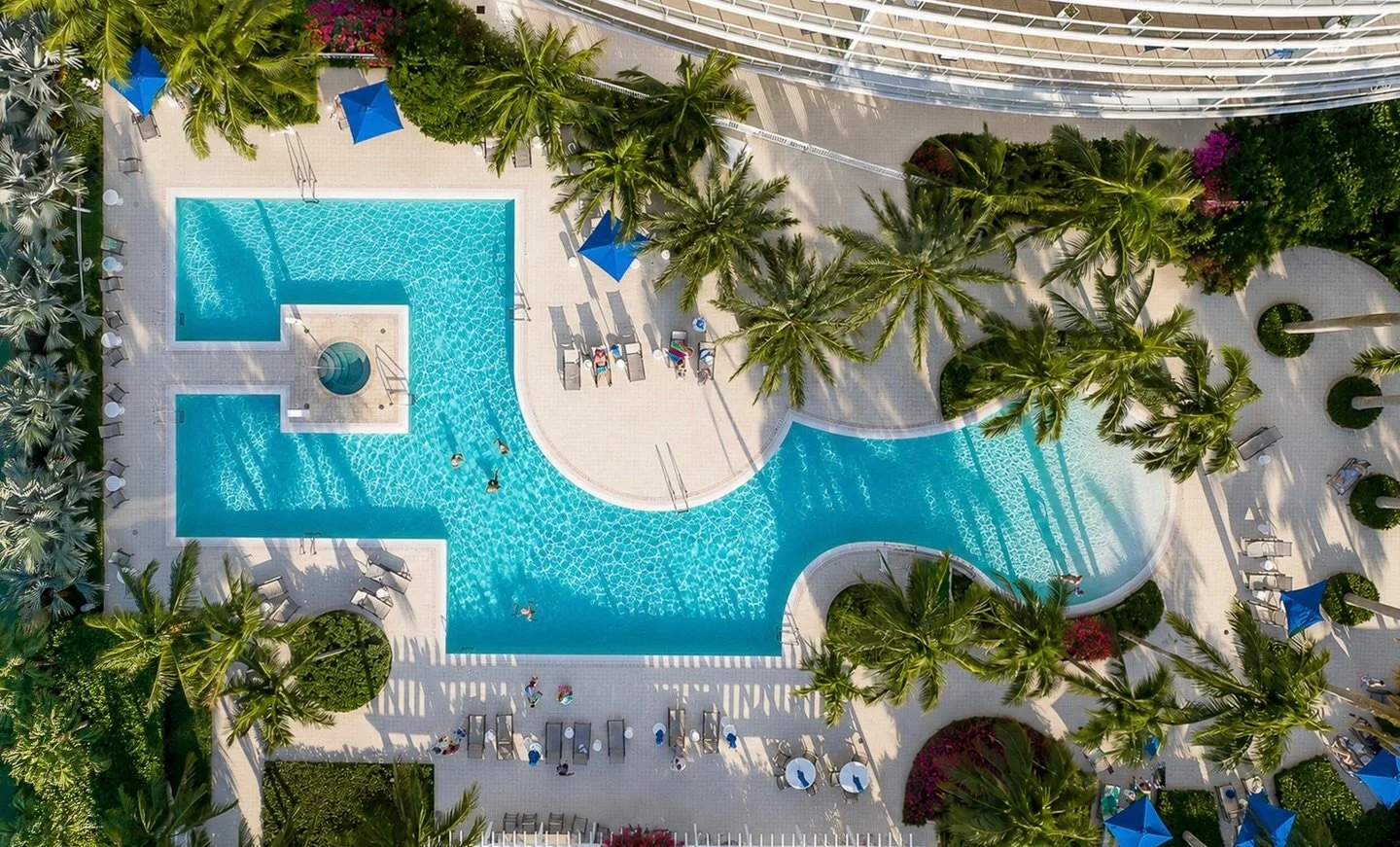 Plaza at Oceanside from above. Sun on the deck, cool water below, palms leaning into the breeze &mdash; the kind of afternoon you book a trip for. This is what your property looks like when it&rsquo;s shot right with quality aerial and hospitality ph