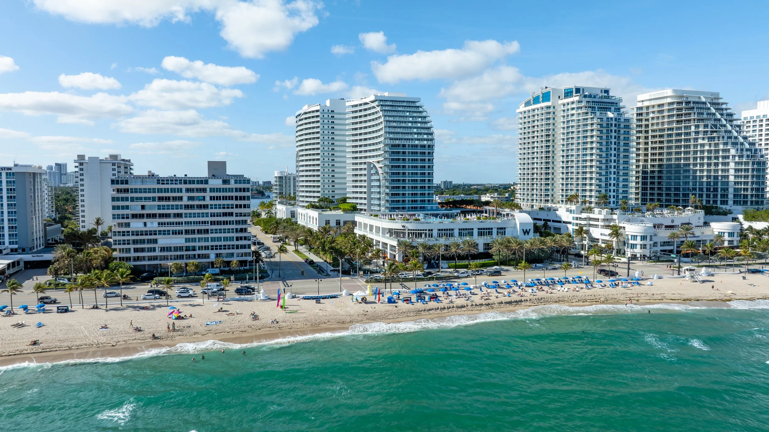 Aerial photograph of beachfront hotels and resorts along the South Florida coastline with turquoise water