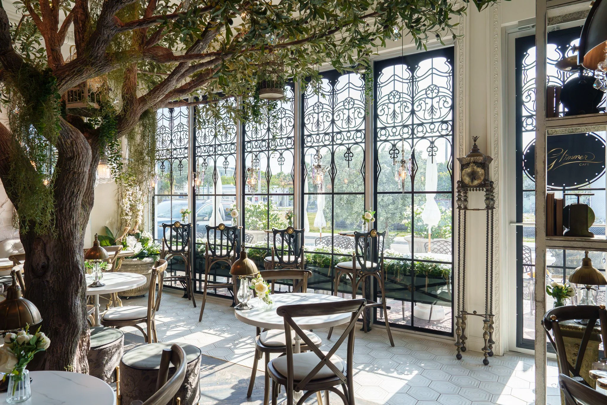 Interior commercial photograph of a renovated South Florida restaurant featuring a large indoor tree and ornate iron windows