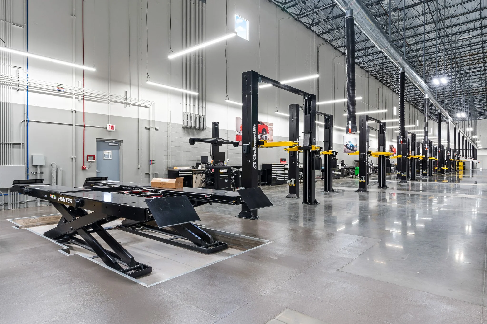 Empty automotive workshop or garage with lift stations, black and yellow hydraulic lifts, and modern lighting fixtures.