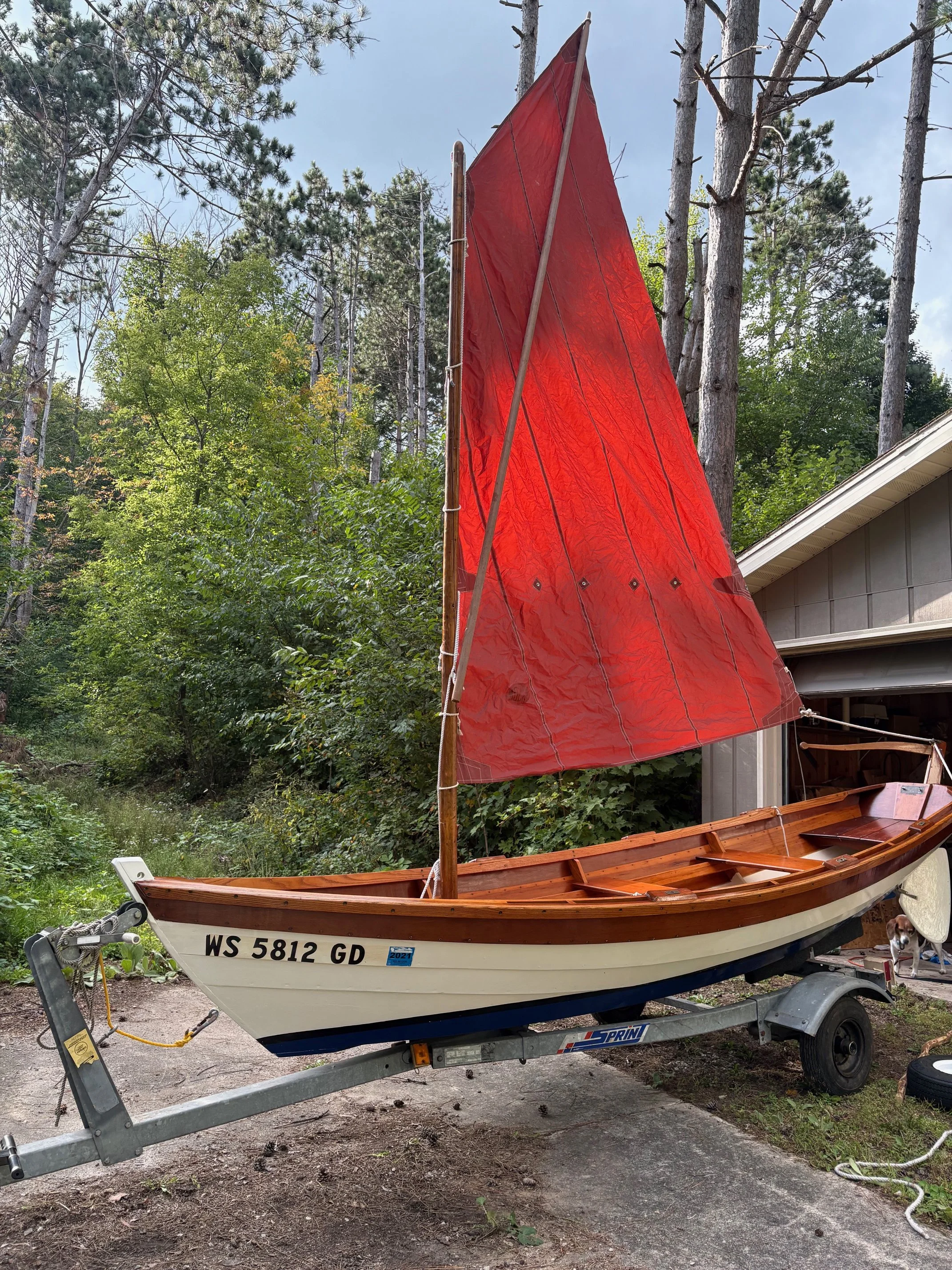 15-foot long Salisbury Point Skiff on a trailer with a red sail raised