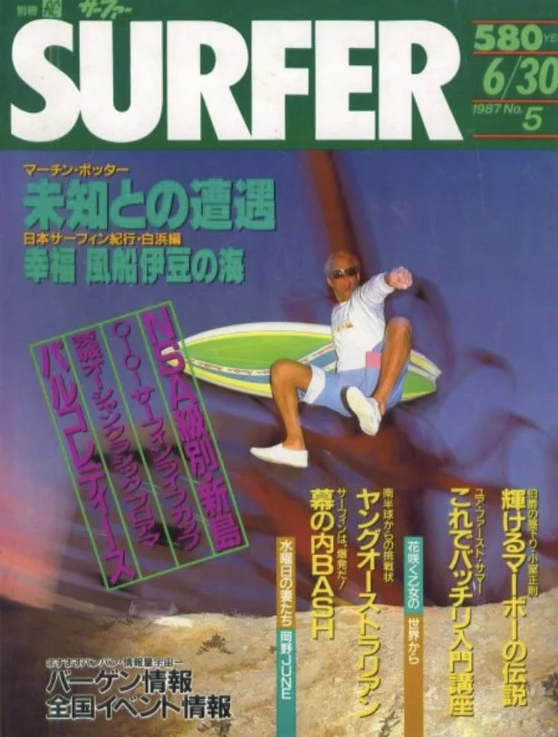 Cover of a Japanese magazine titled 'Surfer,' featuring John Glomb jumping off a ledge, wearing sunglasses, a long-sleeve shirt, and shorts. The cover has prominent Japanese text and a green, white, and purple design.