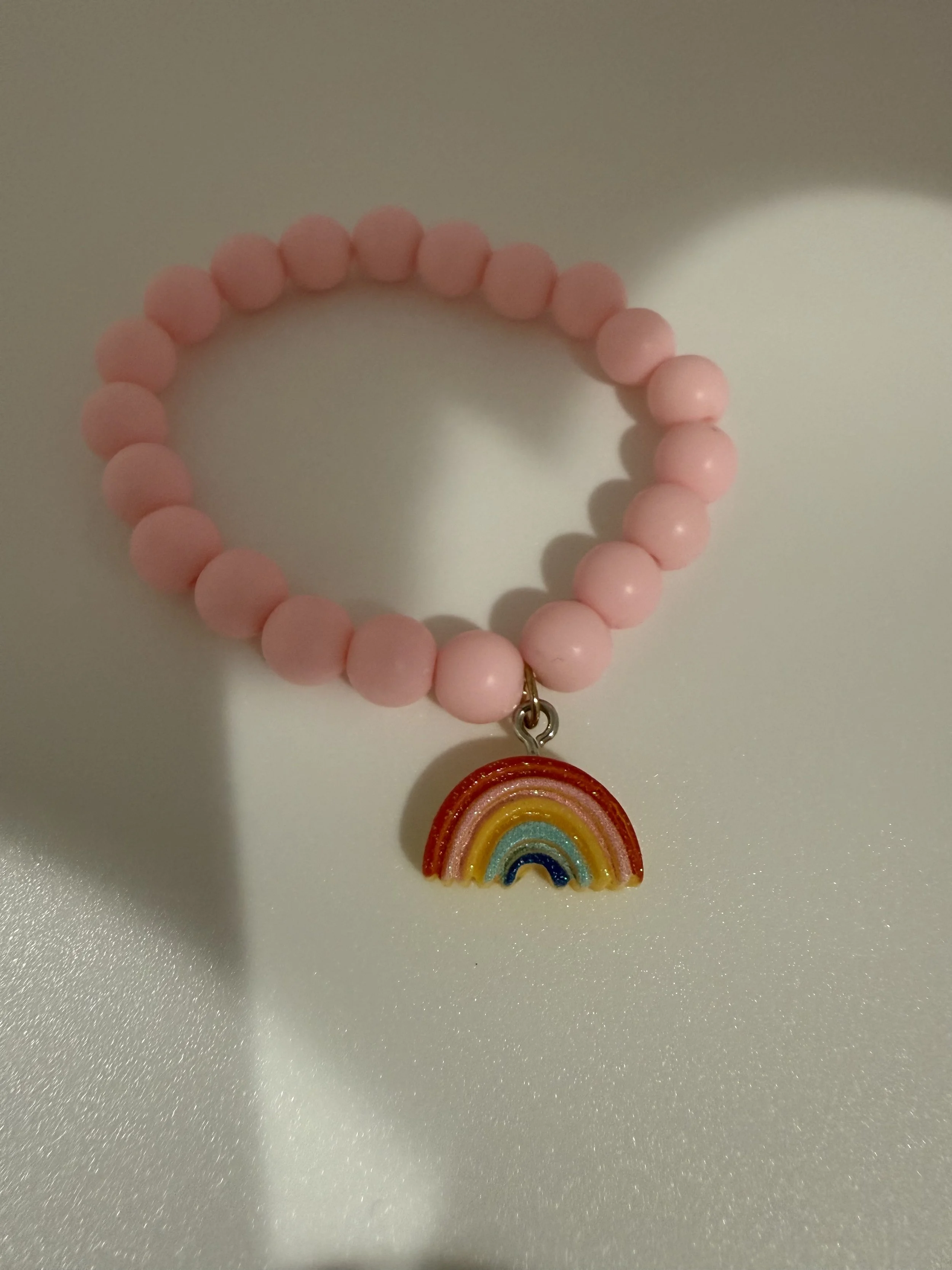 Pink beaded bracelet with rainbow charm
