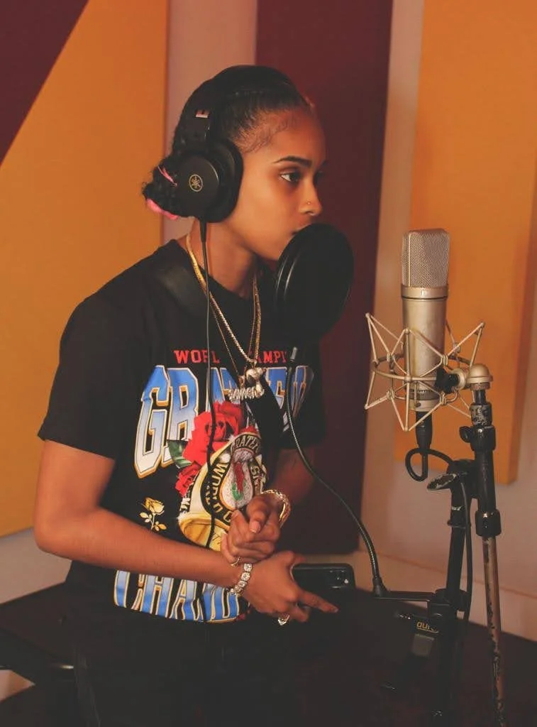 Independent female artist recording vocals in a professional recording studio during an artist development session.
