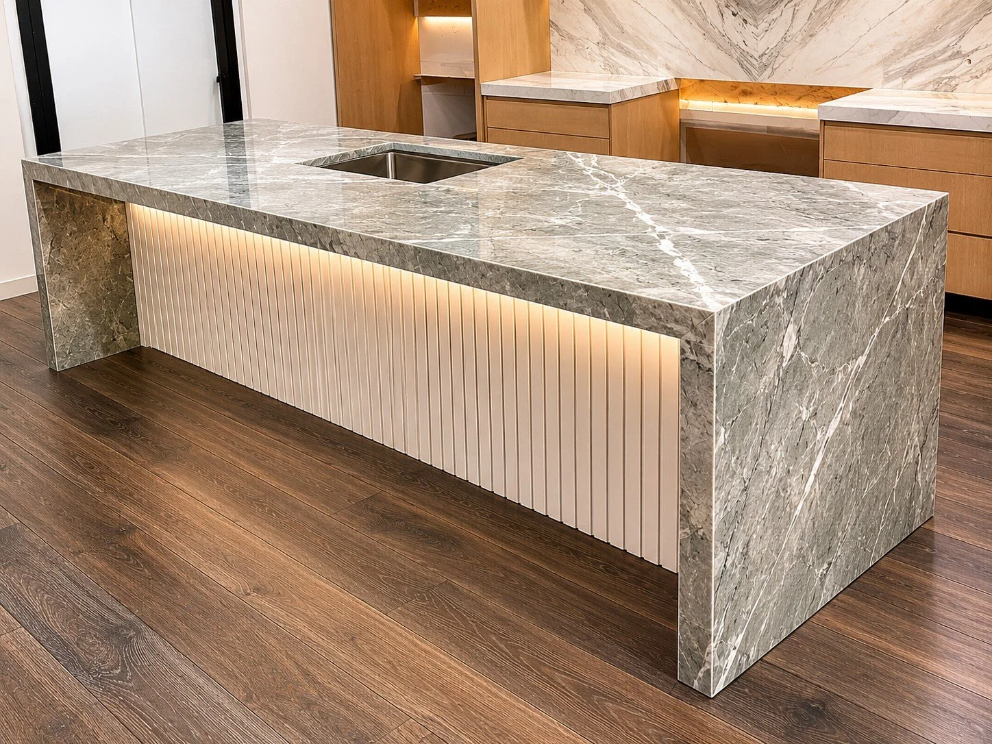 Custom stone island featuring waterfall-edge countertops and precision commercial fabrication.