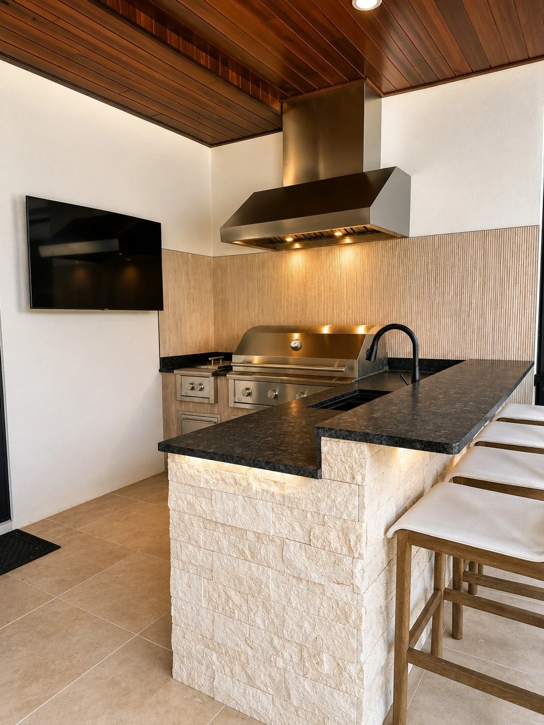 Custom granite countertops installed in a luxury outdoor kitchen with built-in grill and bar seating.
