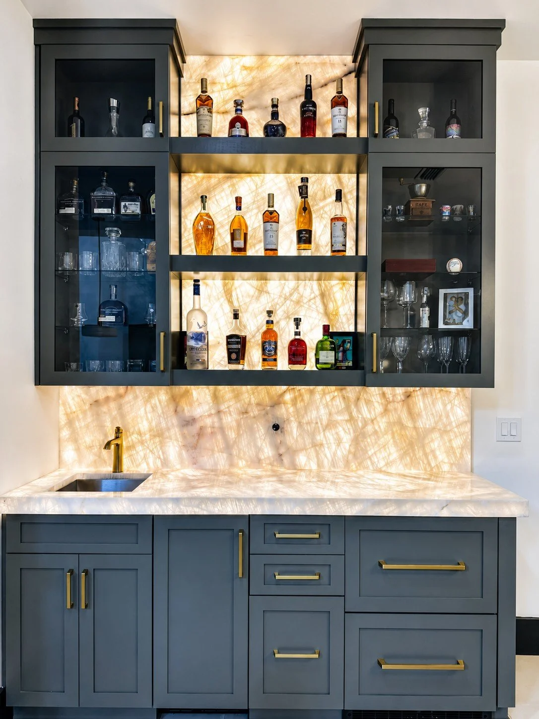 Custom home bar with backlit quartz backsplash, matching quartz countertops, and custom cabinetry.