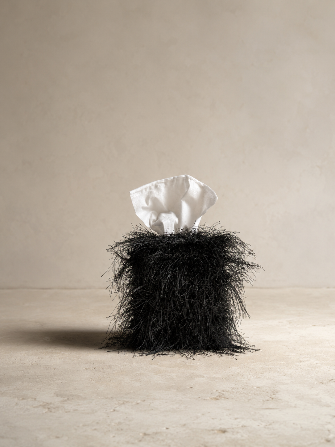 Black eyelash fringe tissue box cover with delicate wispy fibers and dramatic texture, designed as a sculptural decorative accent for luxury interiors.