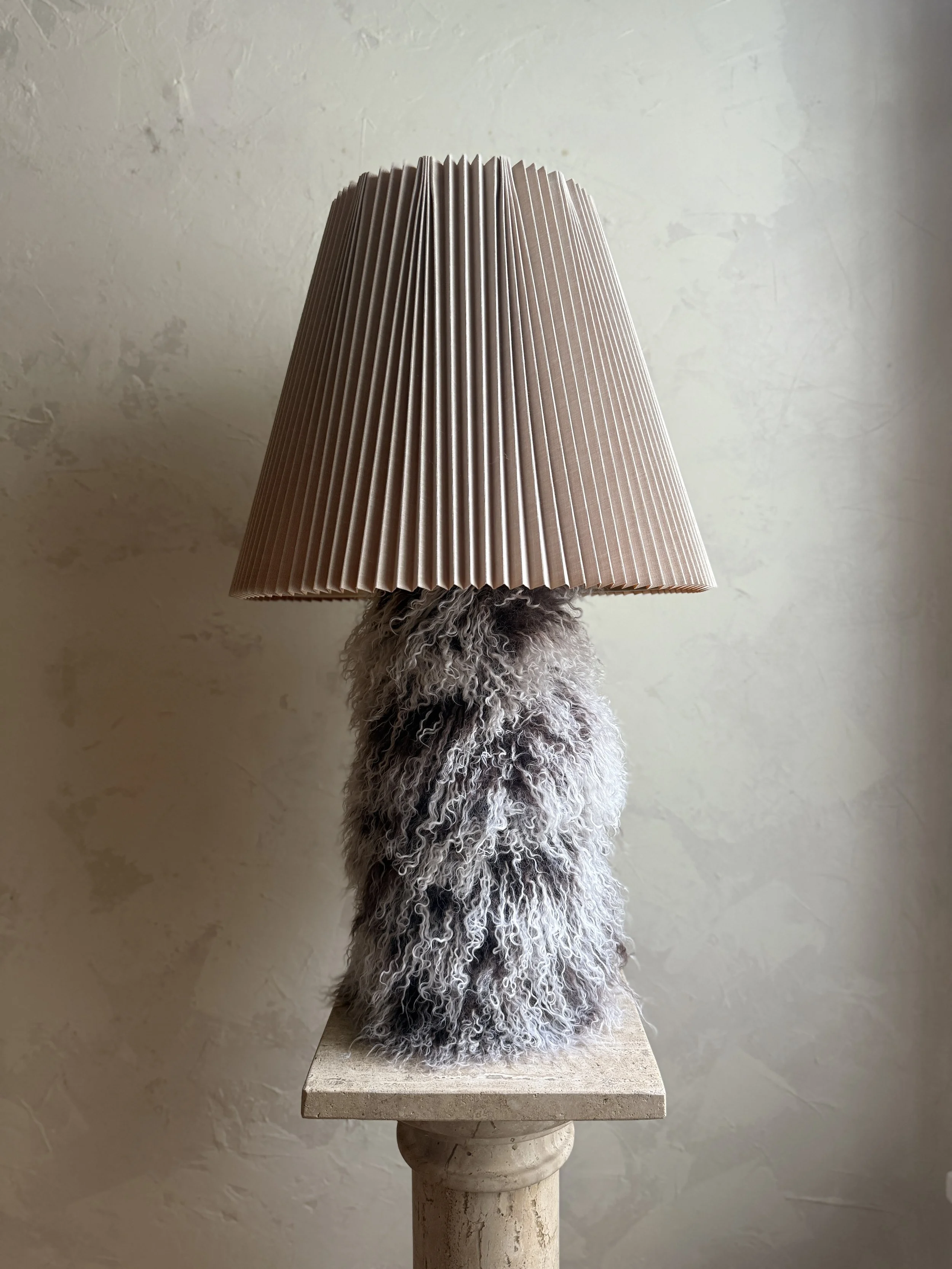 Two-tone Mongolian sheepskin table lamp with pleated shade on display.