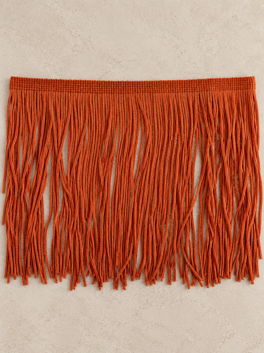 Oxide Orange Spill Edit Fringe Tissue Box Cover by Amber Renee Hansen, featuring cascading deep orange fringe with a subtle sheen and sculptural, floor-pooling movement.