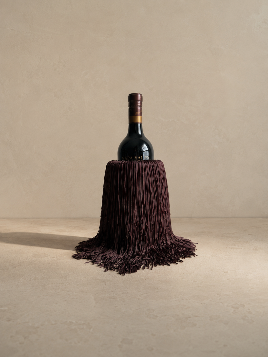 Bordeaux Noir marble wine chiller with cascading fringe, placed on a neutral tablescape.