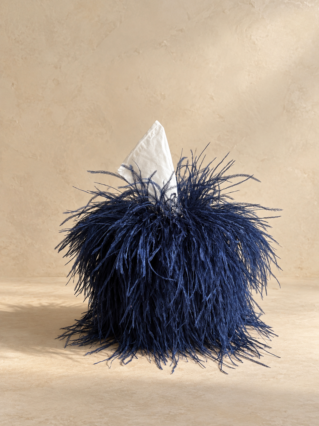 Midnight blue ostrich tissue box cover by Amber Renee Hansen on a warm neutral plaster background