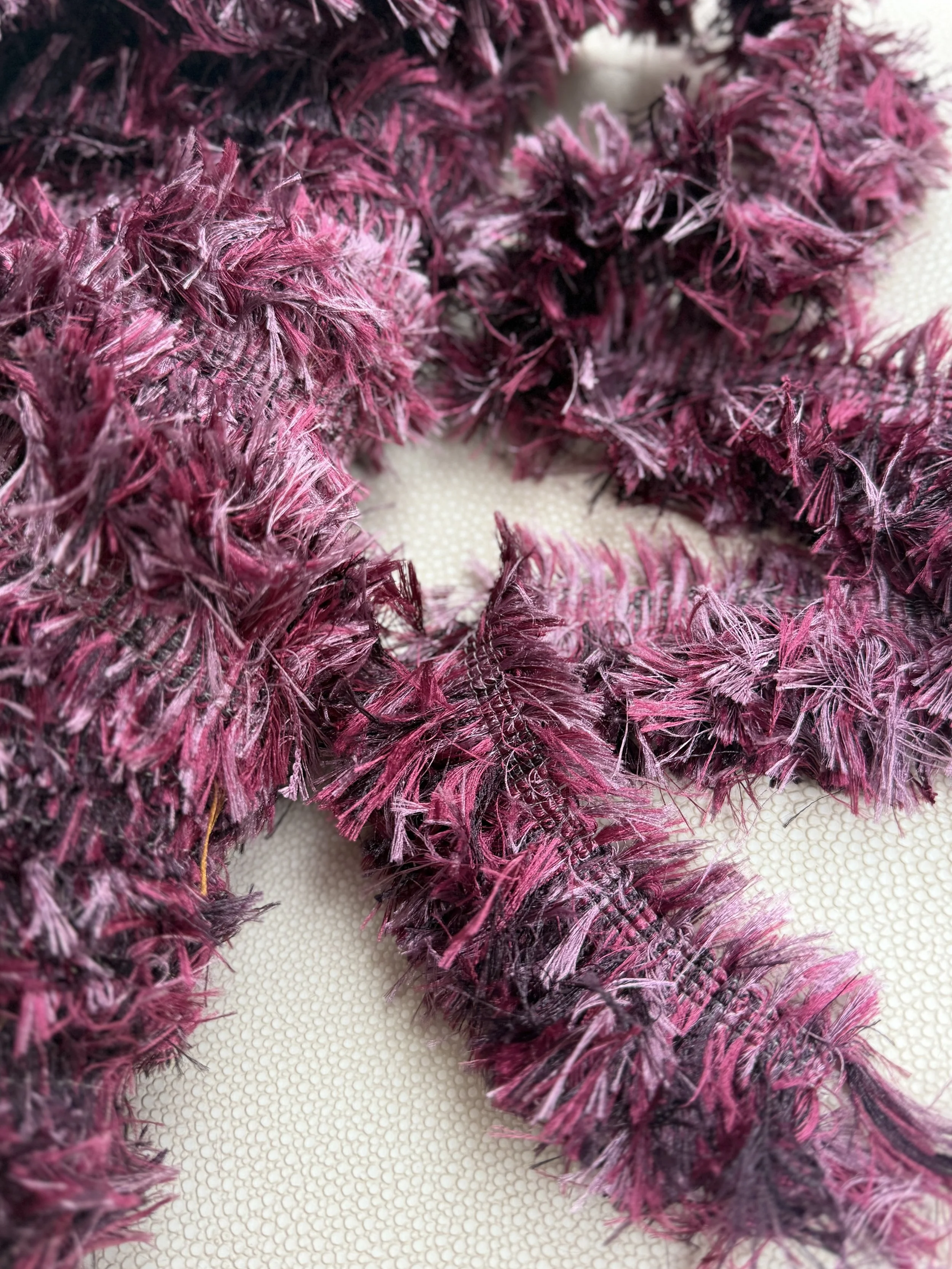 Close-up of the Mulberry Teddy tissue box cover, wrapped in plush fringe in layered mulberry, berry, and plum tones, adding soft texture and sculptural warmth.