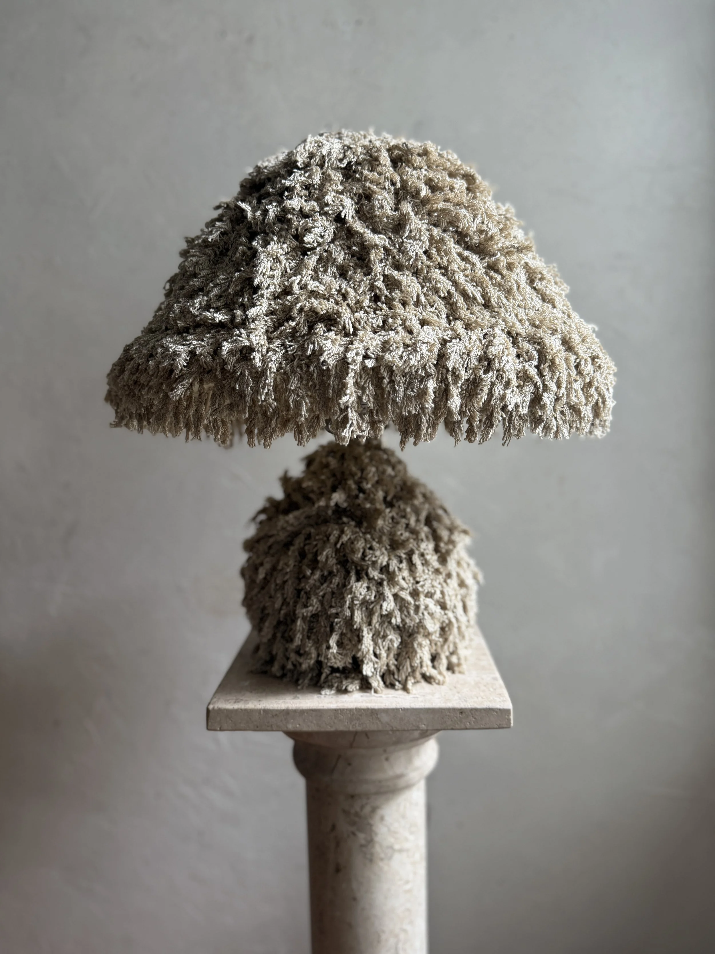 Soft Moss Shag Lamp by Amber Renee Hansen — sculptural fringe-wrapped mushroom lamp in moss tones glowing warmly.