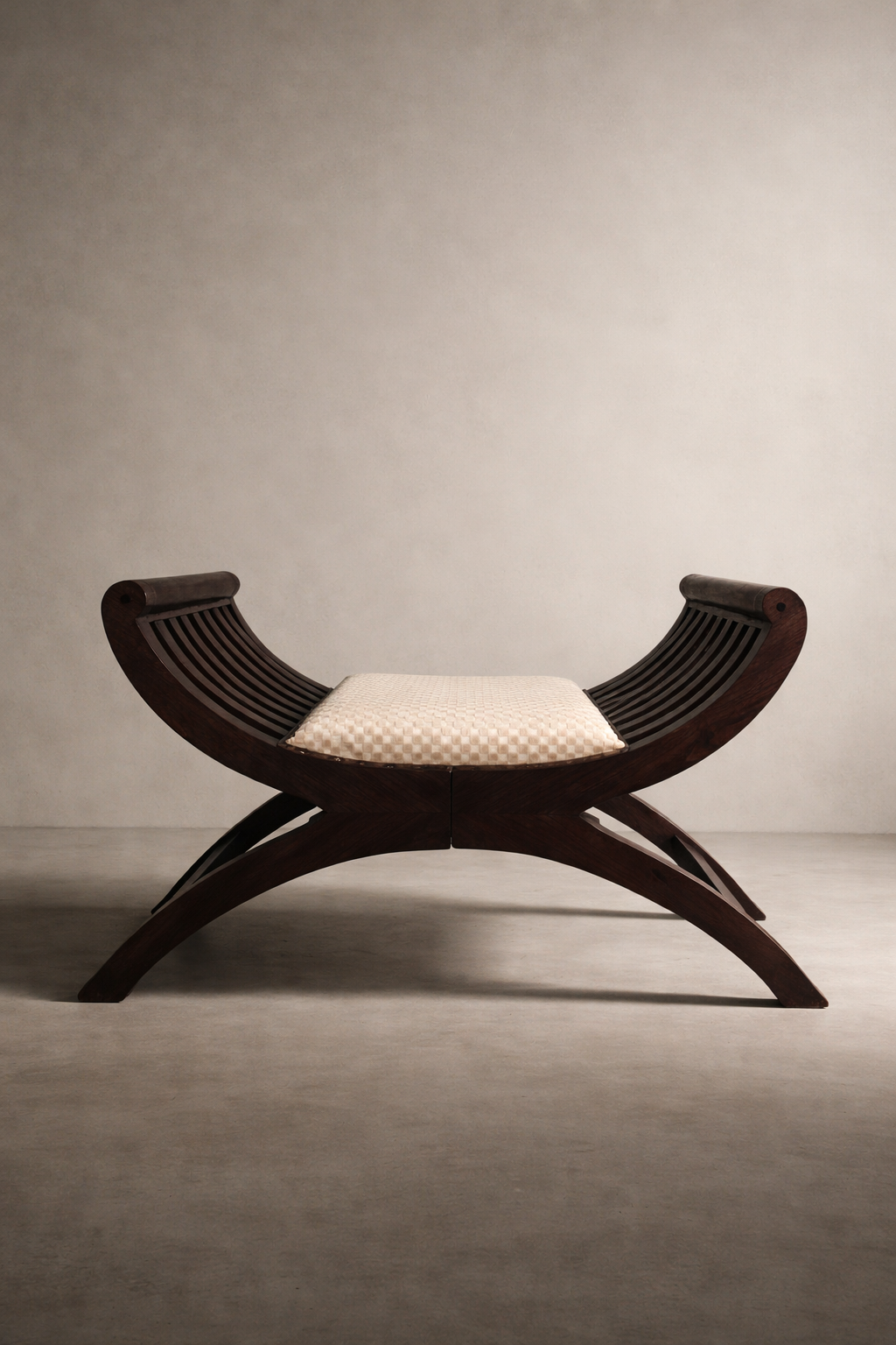Curule X-Frame Bench with espresso wood base and embossed ivory checker seat, photographed in a minimal studio setting.
