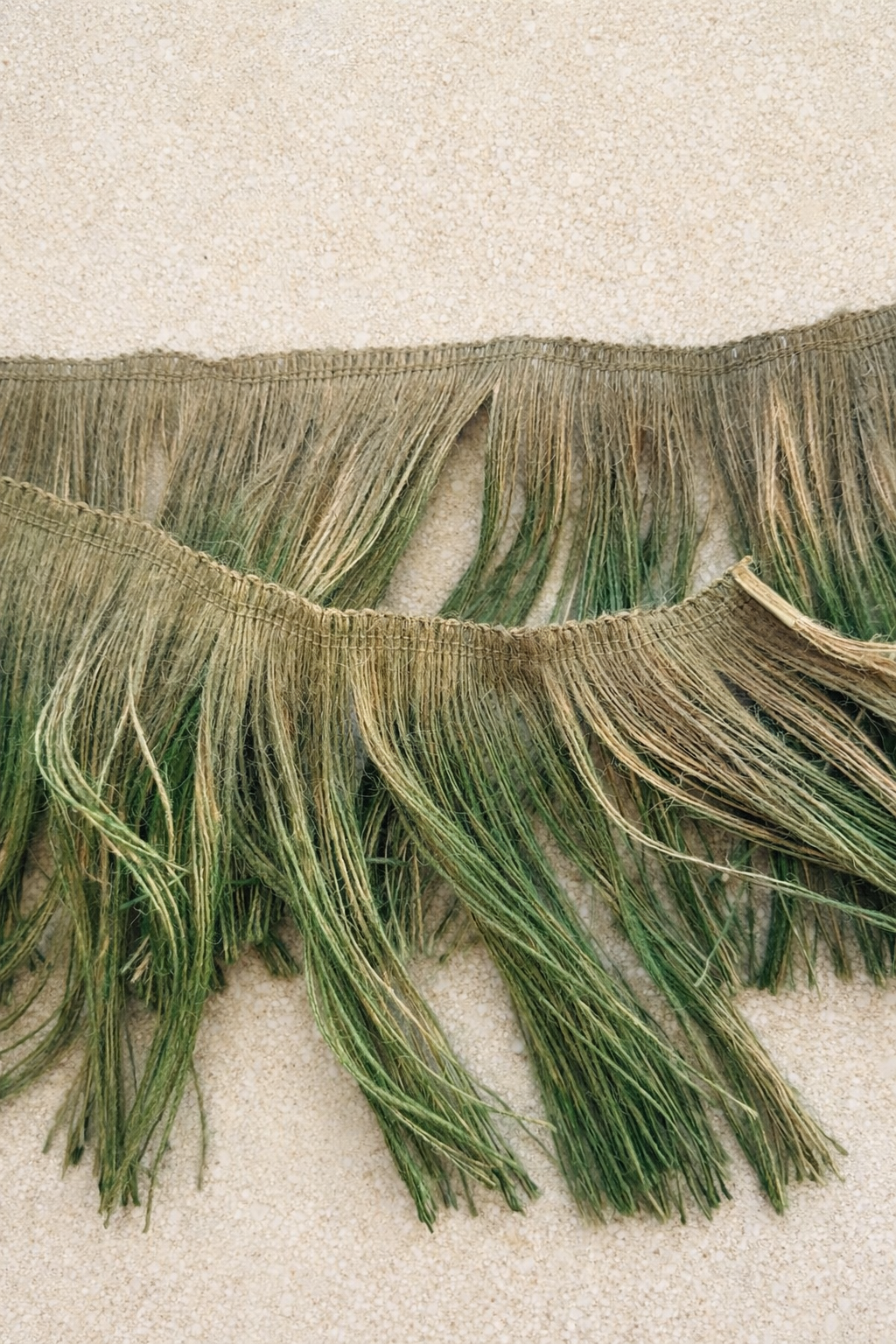 Close-up of tonal green layered jute fringe showing textured grass-inspired fibers.