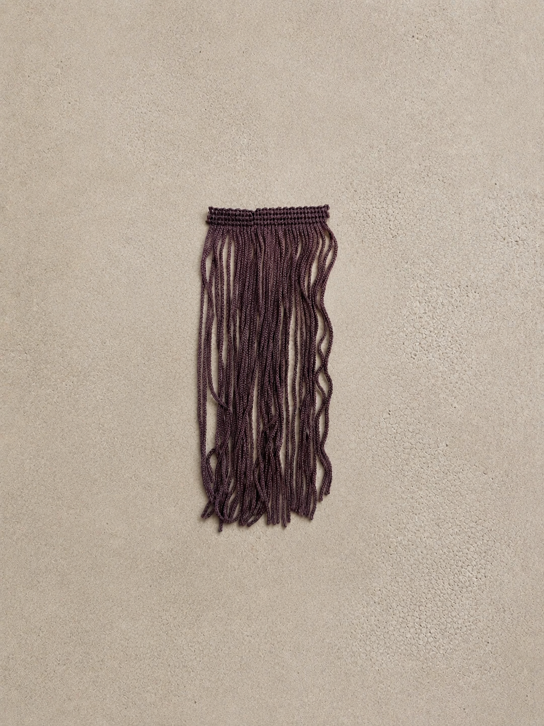 Bordeaux Noir Spill Sphere Vessel with cascading fringe holding burgundy flowers against a warm neutral background.