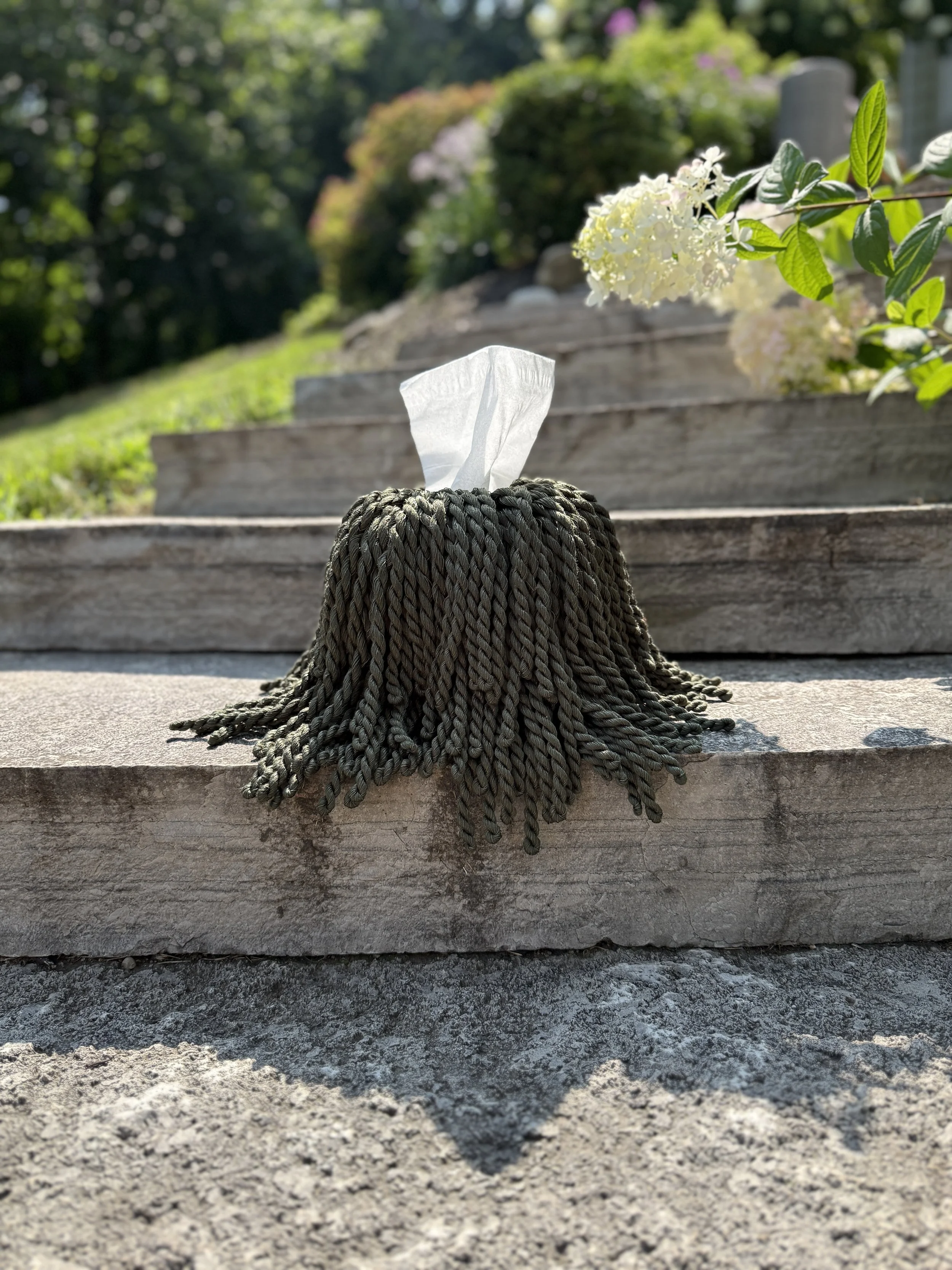 Forest Shadow fringe tissue box cover in dark moss green styled in a refined interior setting, oversized sculptural drape.