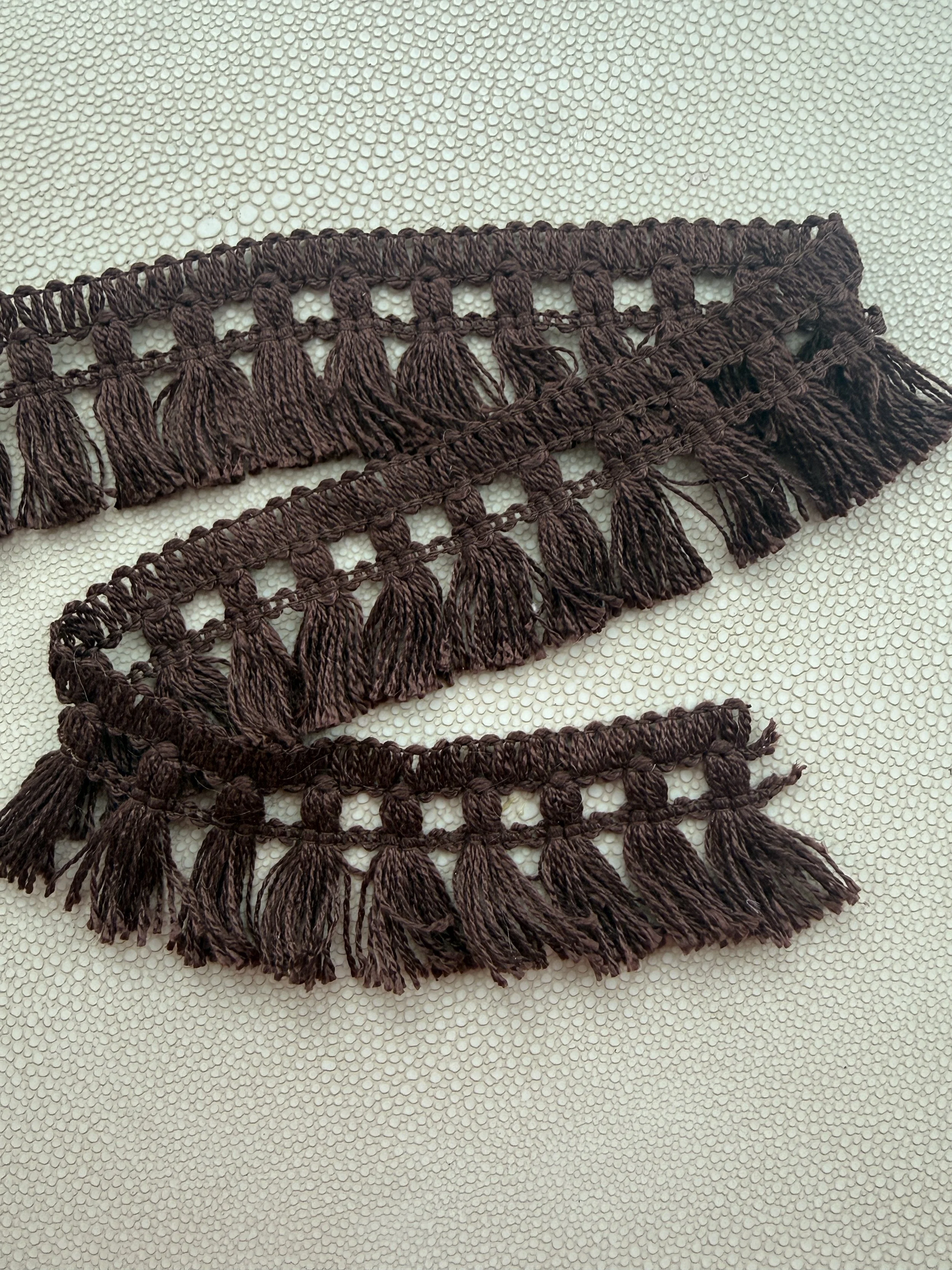 Messy Mahogany Brown fringe tissue box cover on a textured stone surface with a soft neutral wall background