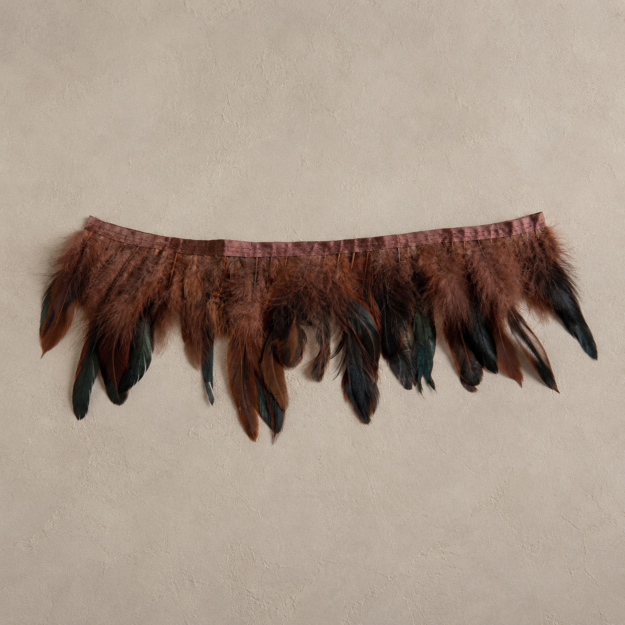 Close-up detail of chestnut and tobacco rooster feathers with dark ebony accents on tissue box cover.