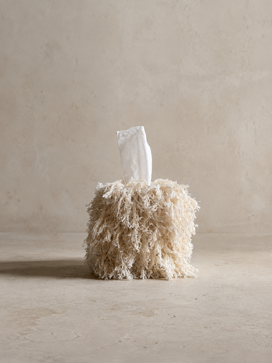 Decorative tissue box cover in Undone Muslin with layered cotton fringe and a warm natural textile-inspired finish.