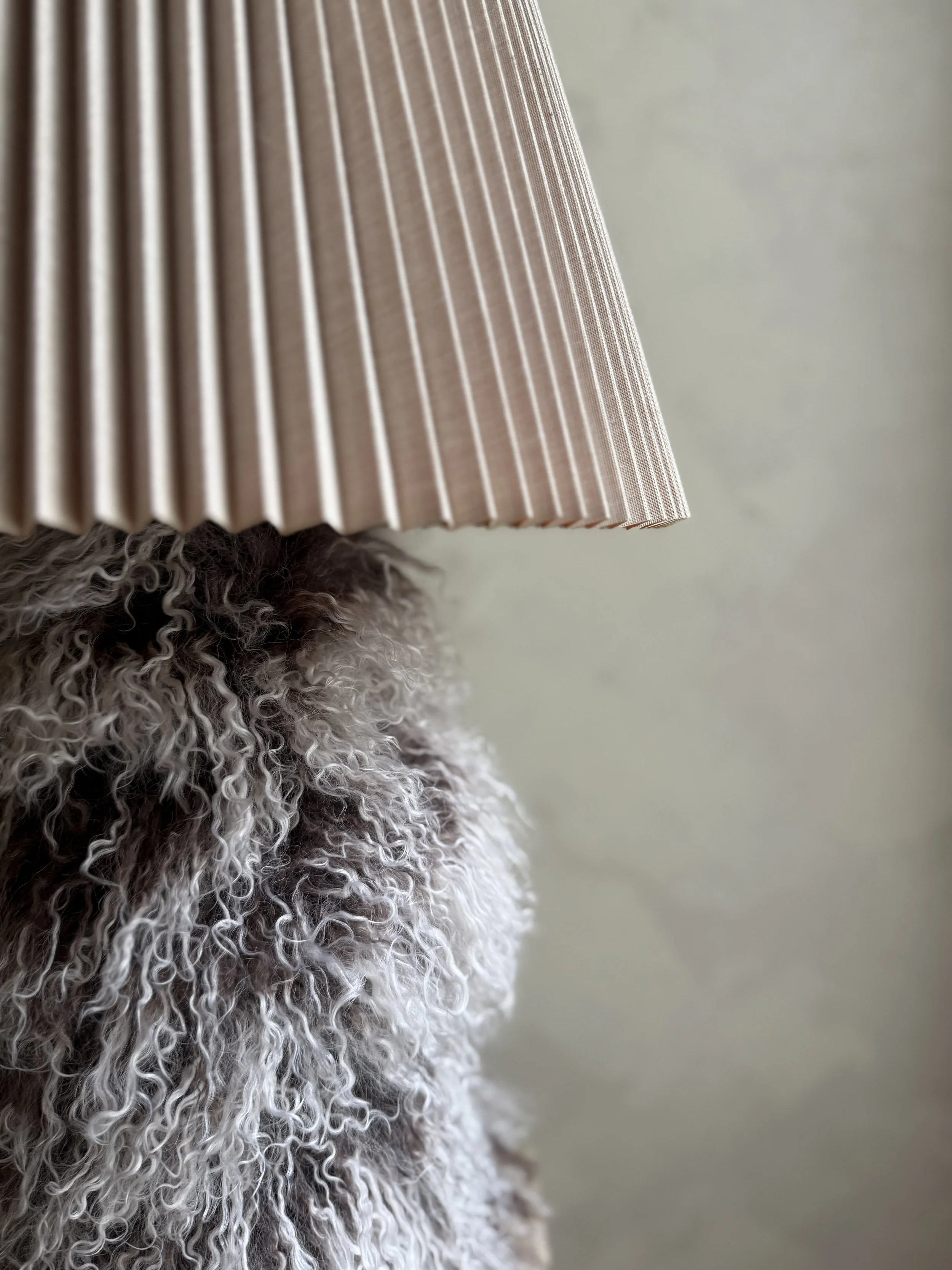 Two-tone Mongolian sheepskin table lamp with pleated shade on display.