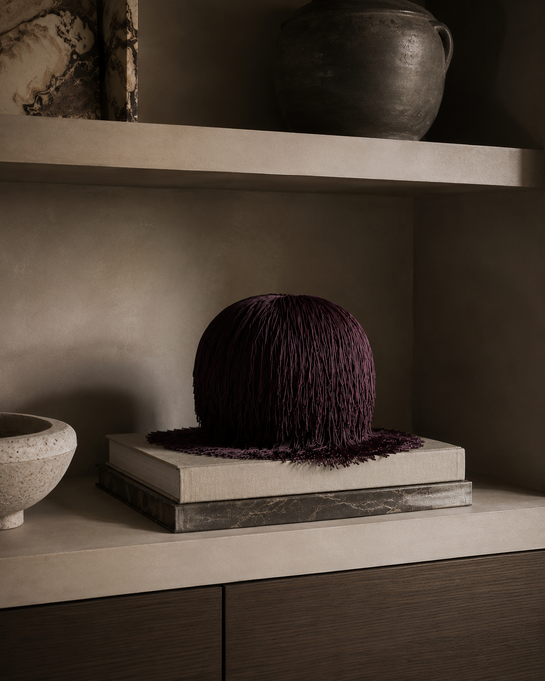 Bordeaux Noir Spill Sphere Vessel with cascading fringe holding burgundy flowers against a warm neutral background.
