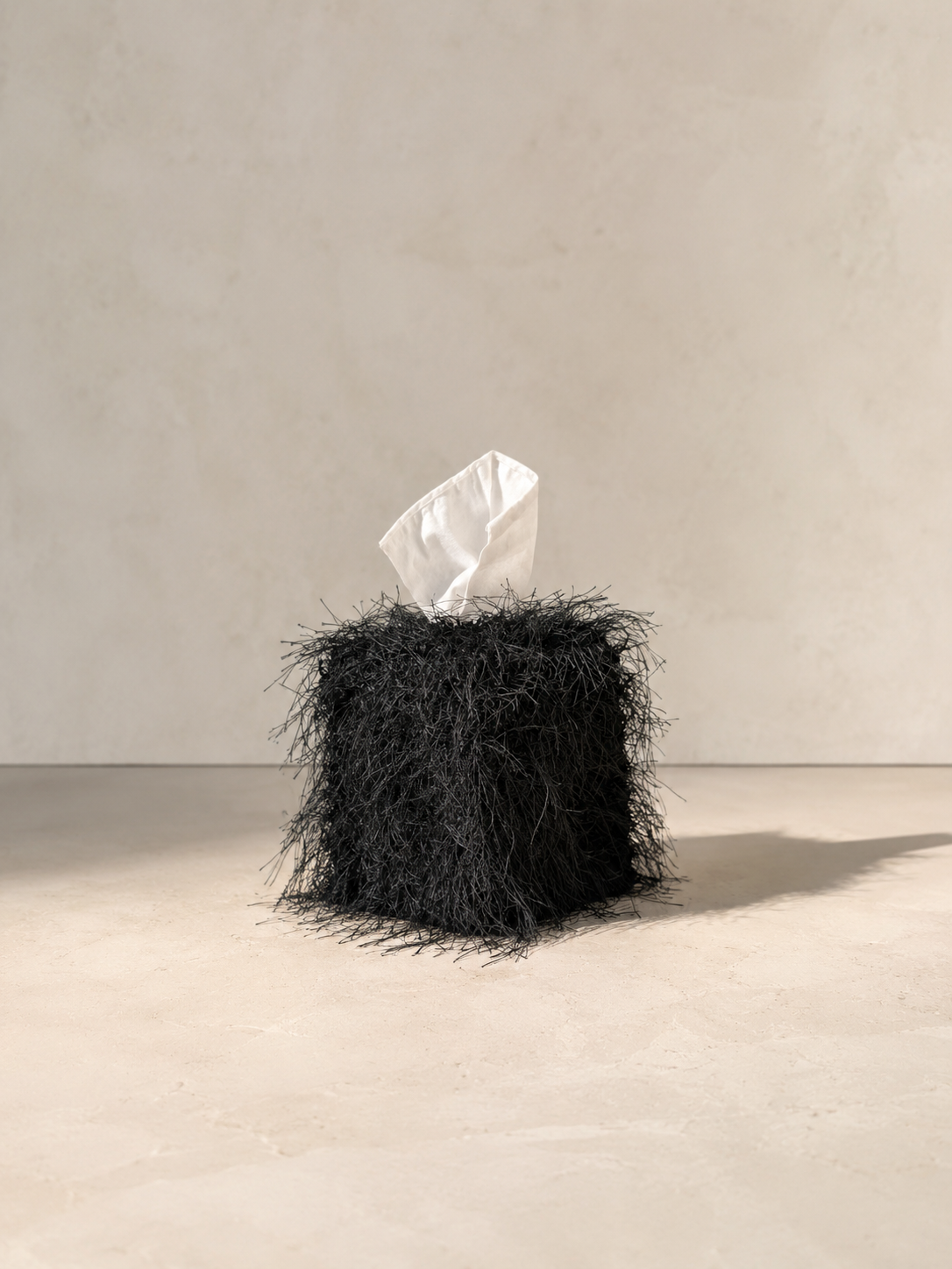 Black eyelash fringe tissue box cover with delicate wispy fibers and dramatic texture, designed as a sculptural decorative accent for luxury interiors.