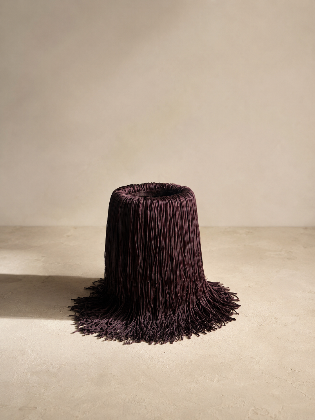 Fringe-wrapped wine chiller in an editorial setting, with wine bottle inside and subtle background.
