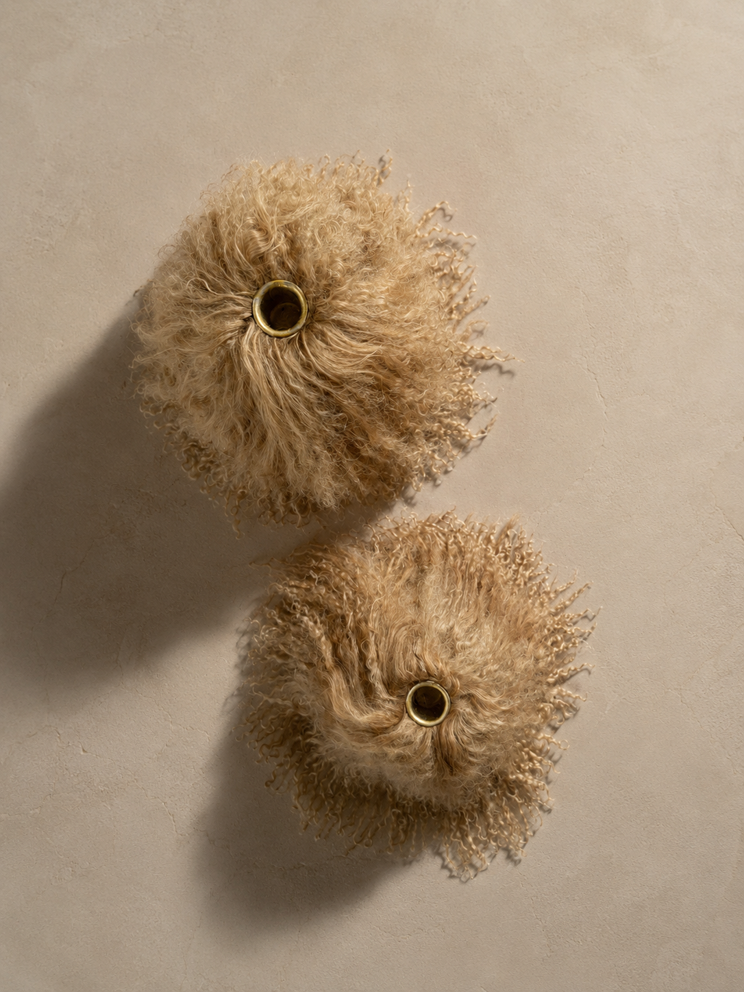 Overhead view of two Miso Mongolian lamb taper holders with ivory candles, showcasing the organic shape and natural drape of the lamb.