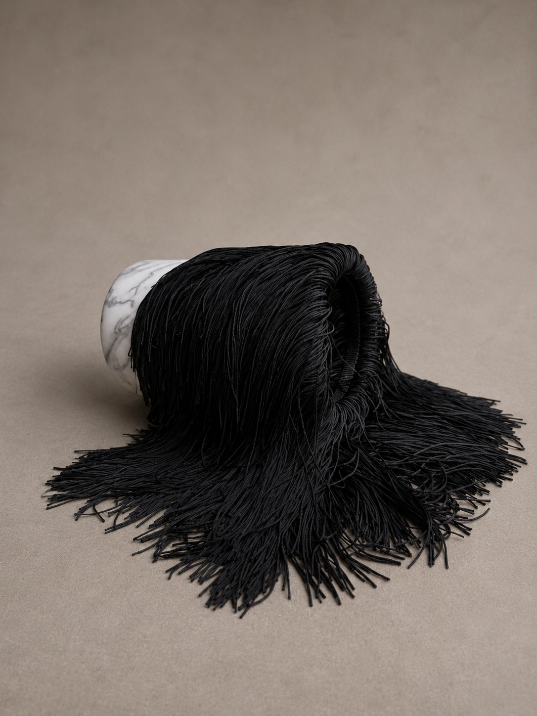 The black fringe marble wine chiller tipped on its side, revealing the natural marble base and the elegant fringe cascading along the side.