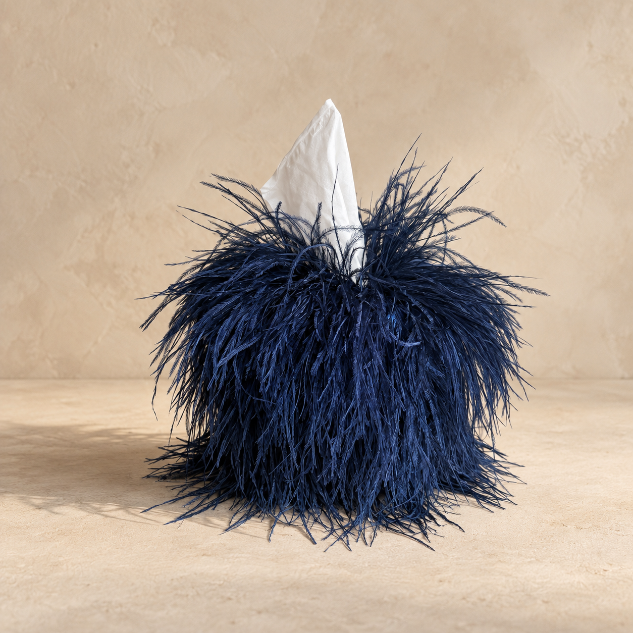 Midnight blue ostrich tissue box cover by Amber Renee Hansen on a warm neutral plaster background