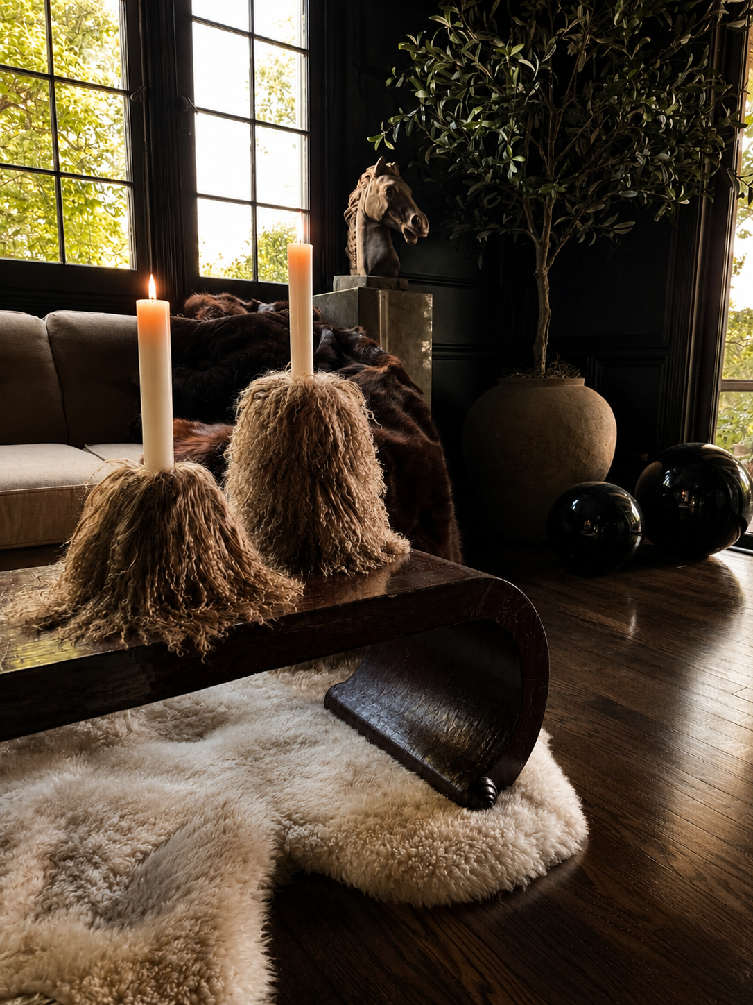 Pair of Miso Mongolian lamb taper candle holders with ivory taper candles, photographed against a warm neutral background with soft directional light.