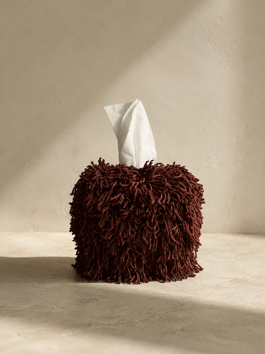 The Limited Edition Cordovan Fringe Tissue Box Cover styled in a warm neutral interior, showcasing rich cordovan fringe with soft movement and understated luxury.