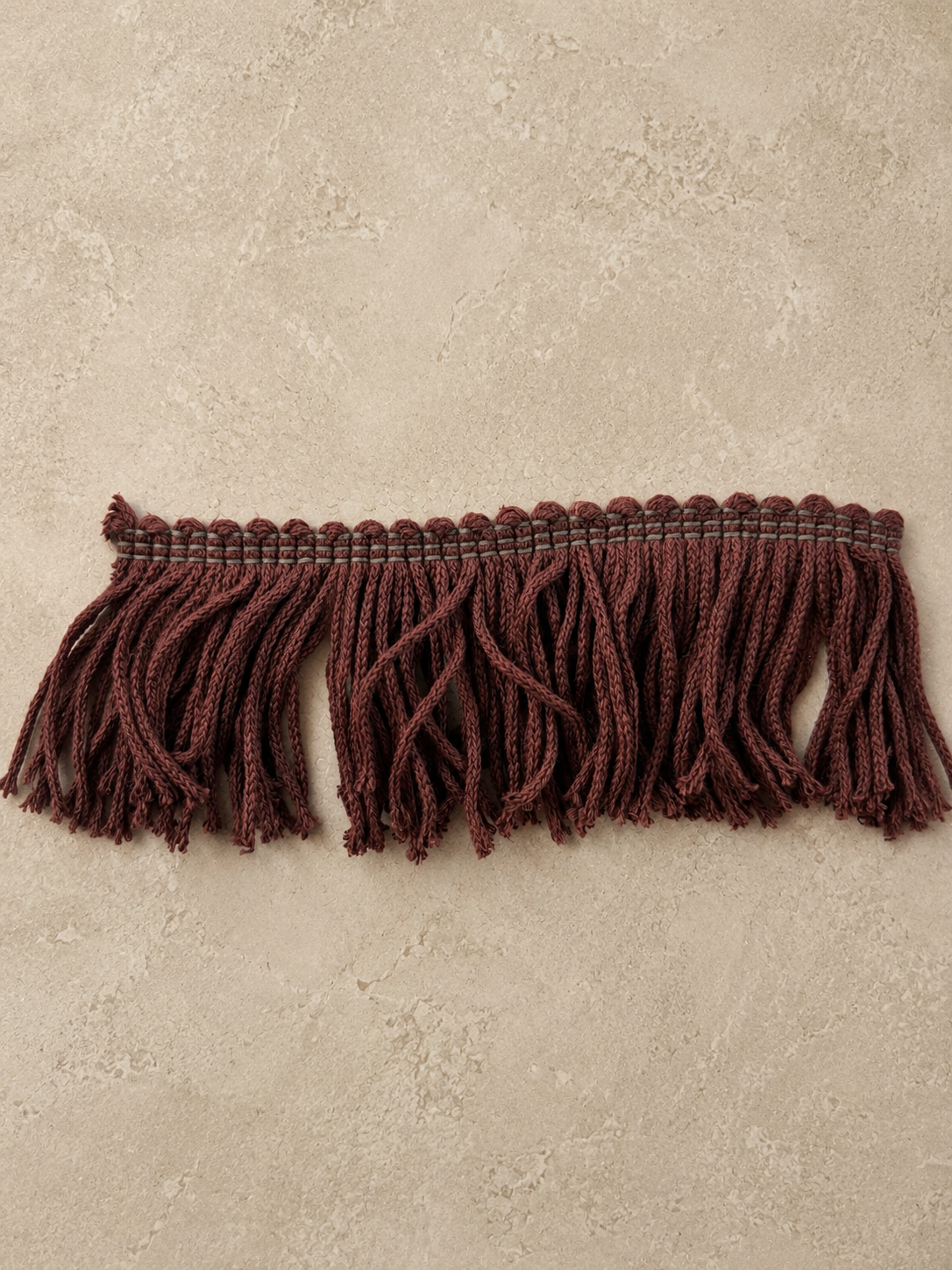 Front view of the Limited Edition Cordovan Fringe Tissue Box Cover wrapped in rich cordovan fringe with layered texture and movement, photographed in an editorial studio setting.