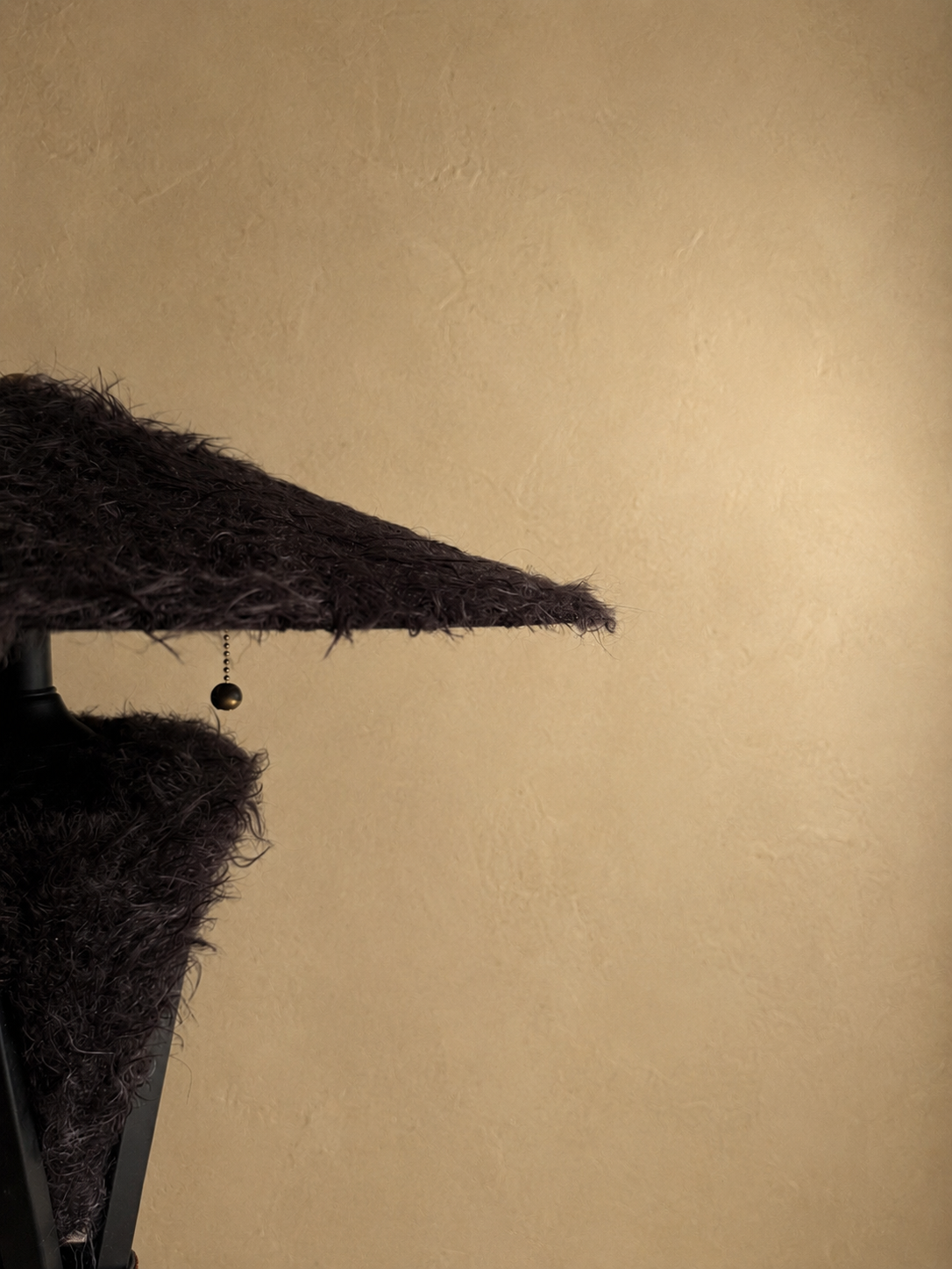 Triphora sculptural table lamp by Amber Renee Hansen with a deep brown faux fur amphora form and wide faux fur shade, black tripod frame, and wrapped cord detail.