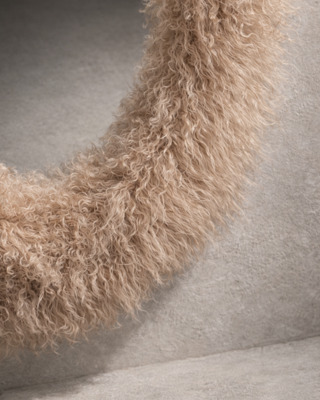 Capsule-shaped wall mirror wrapped in Mongolian lamb sheepskin with elongated vertical form