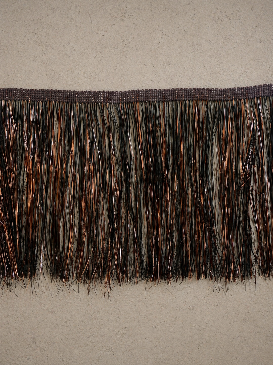 Burnt mahogany static tinsel fringe tissue box cover with reflective layered texture in a warm luxury interior