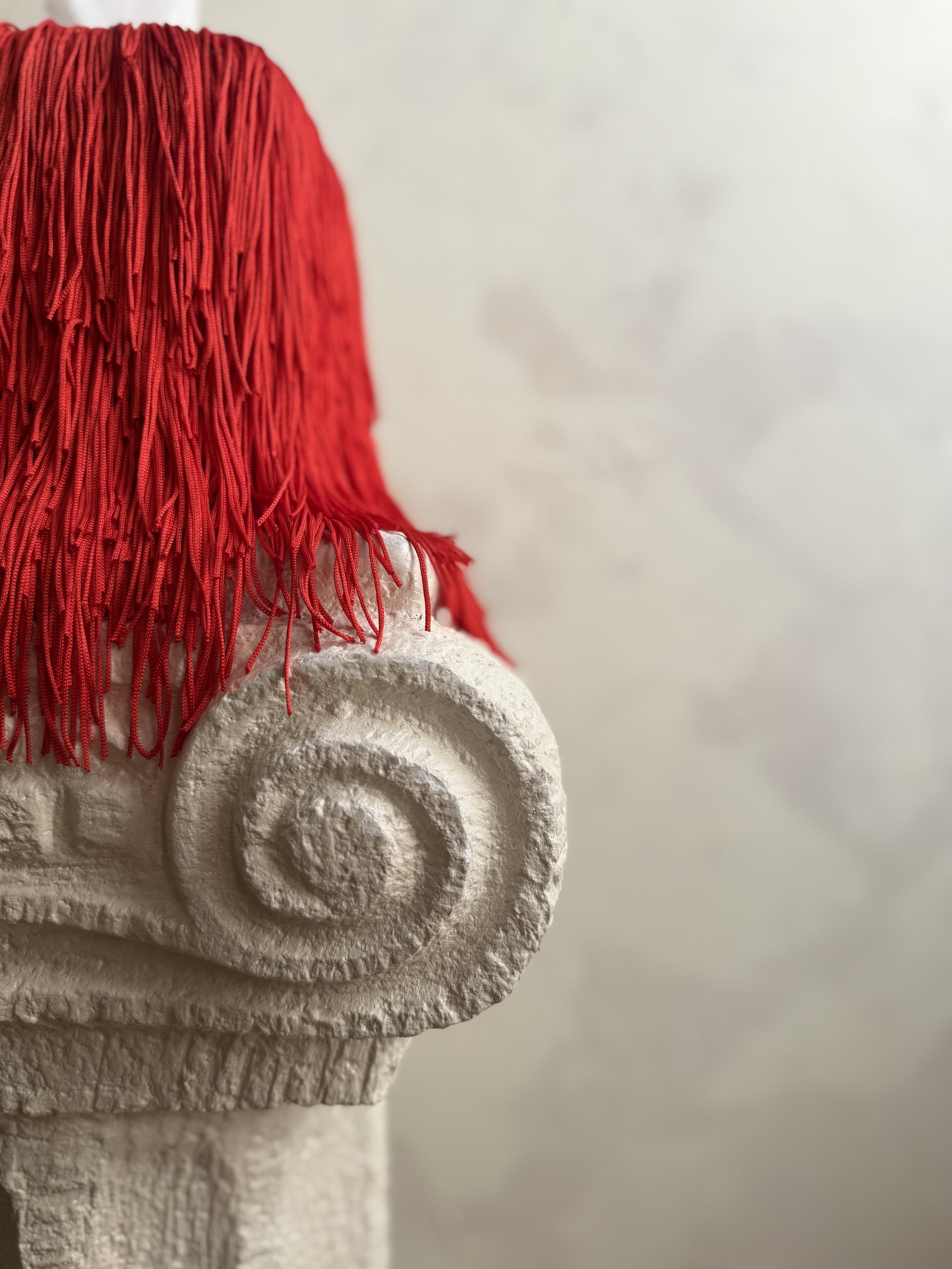 Close-up of vermillion fringe detail draping softly on a tissue box cover.